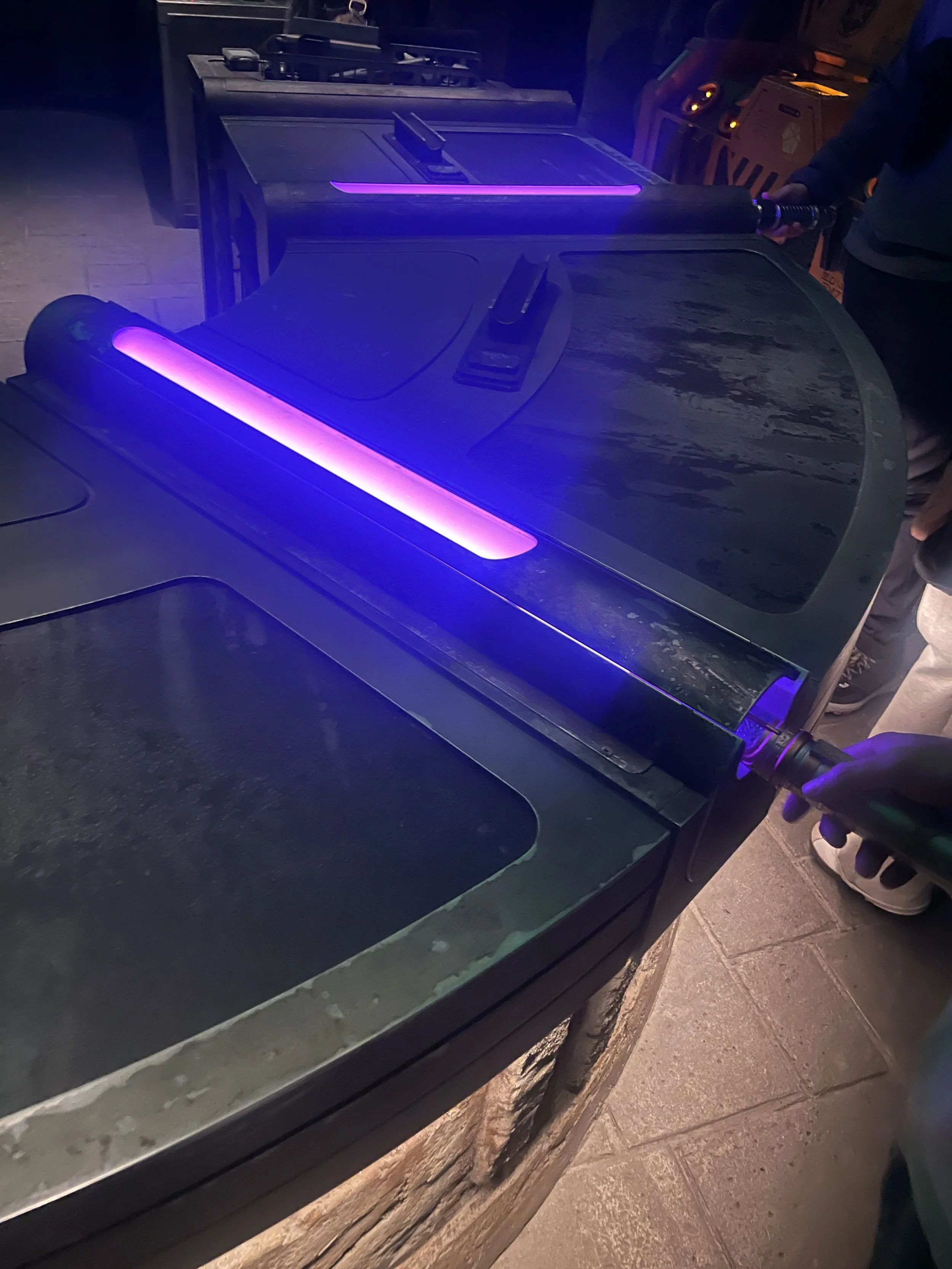 A person using a handheld UV light to inspect a surface, with ultraviolet glow highlighting the area.