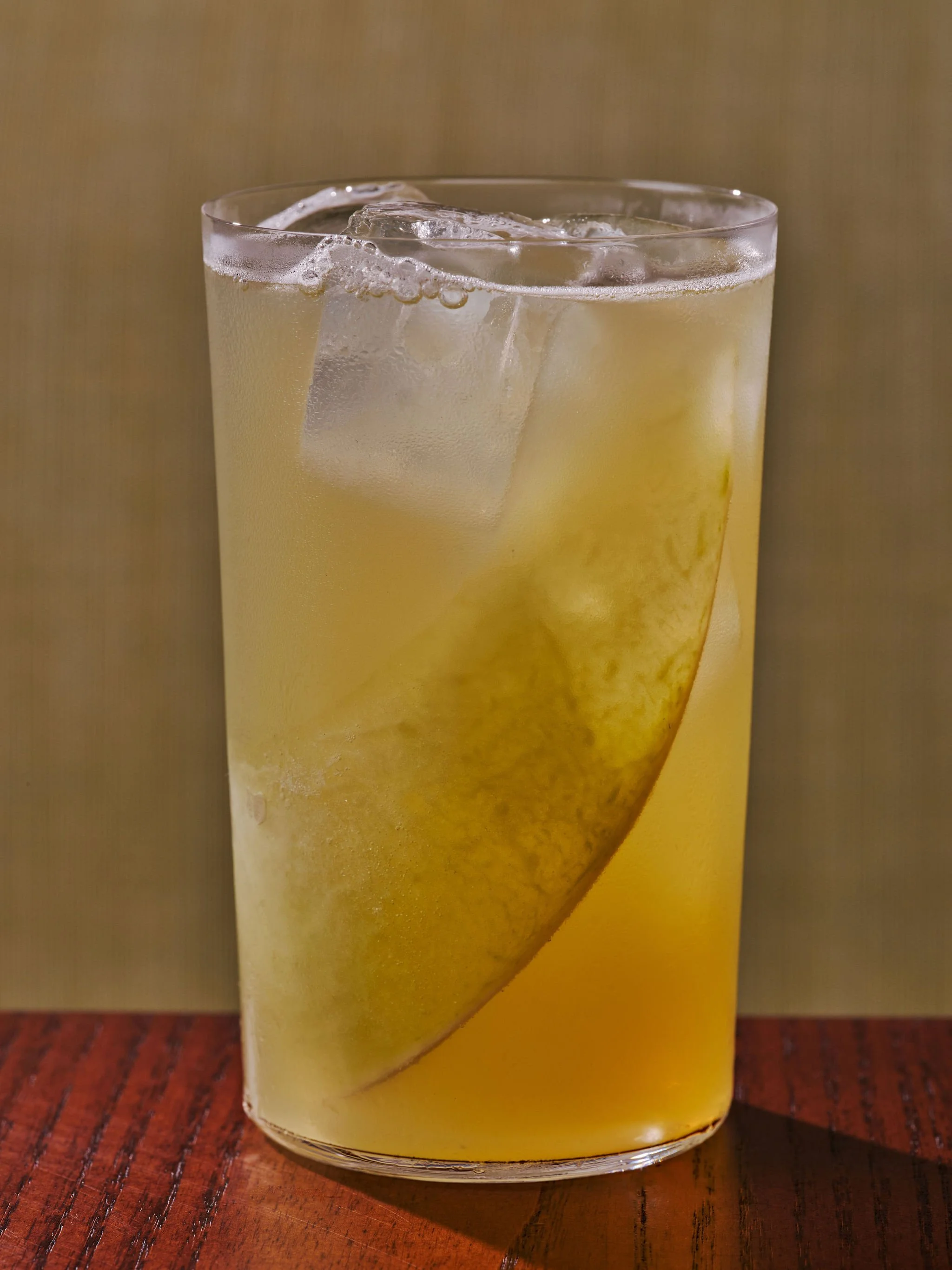A tall glass of lemonade with ice cubes and a lemon slice.