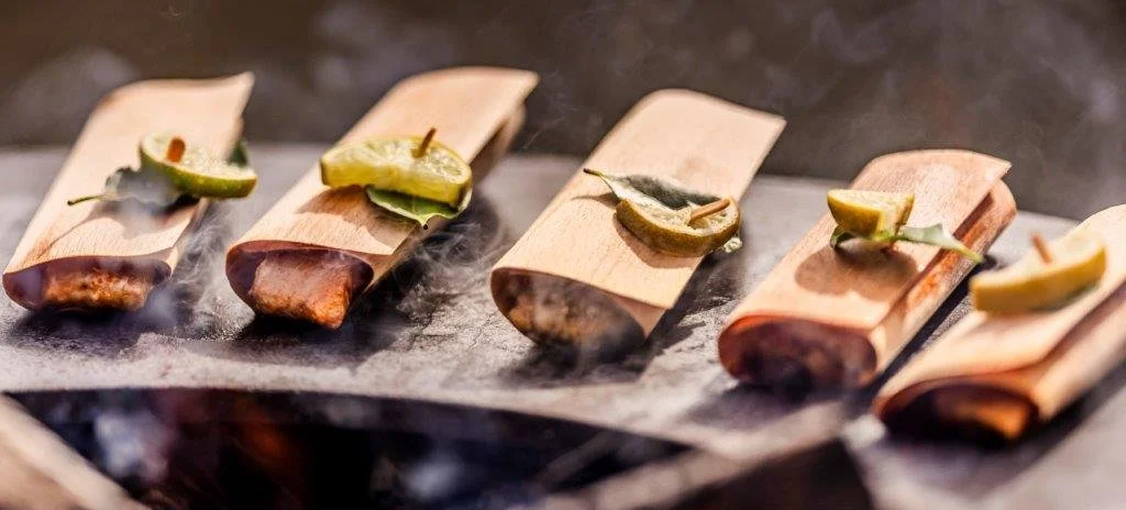 Röllchen auf Backpapier, mit Zitronenscheiben und Gewürzen, beim Grillen