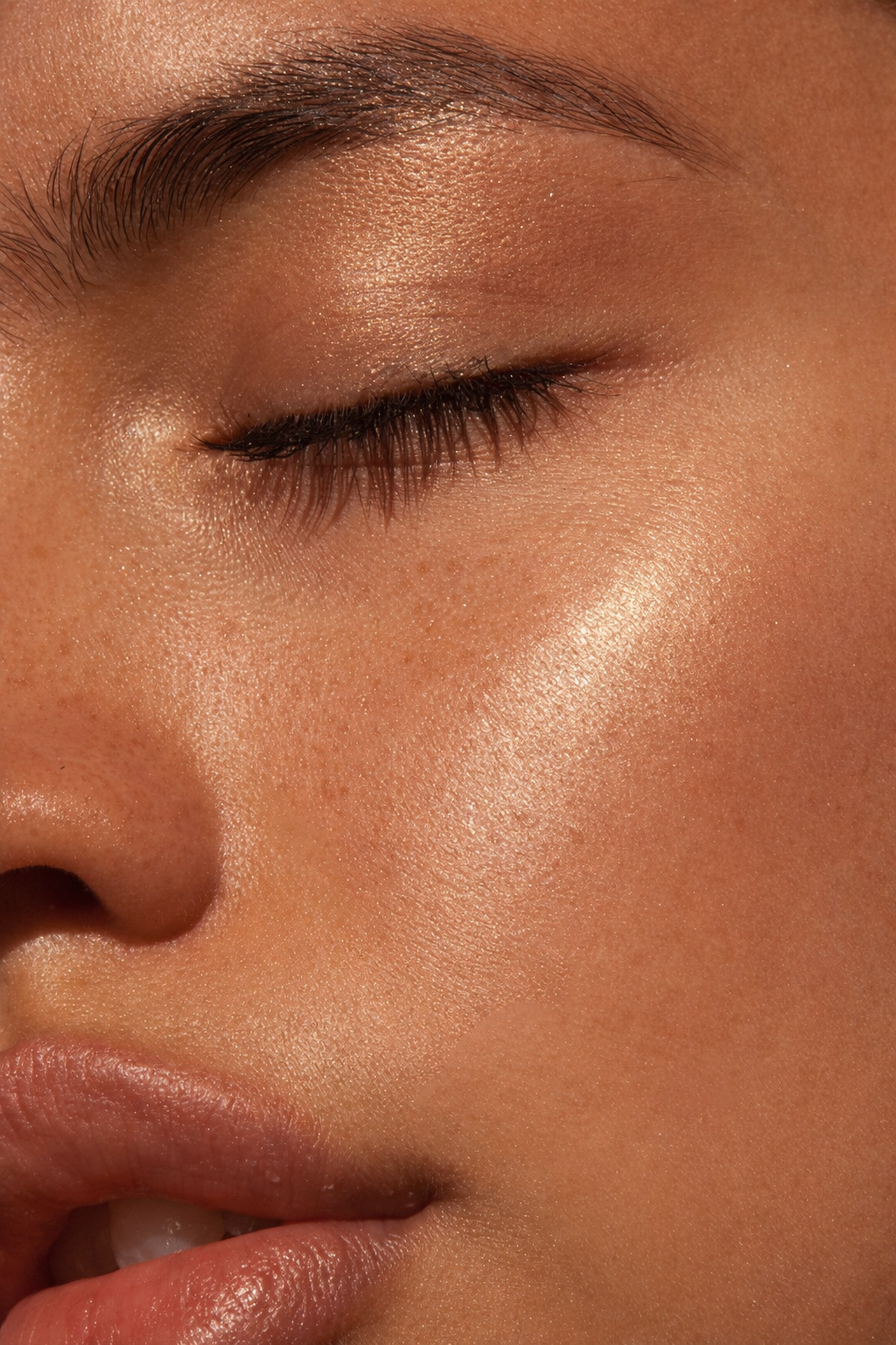 Close-up of a person's face with closed eye, smooth skin, and makeup highlighting cheekbone.