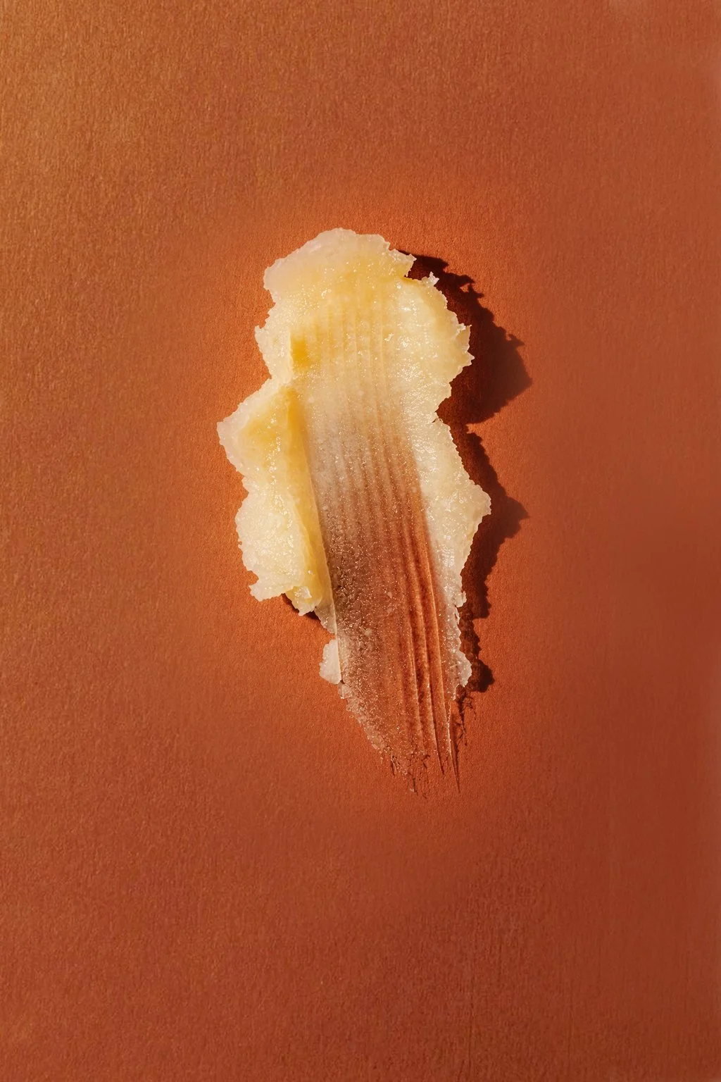 A torn piece of tape with a brown streak in the middle on a plain orange background.