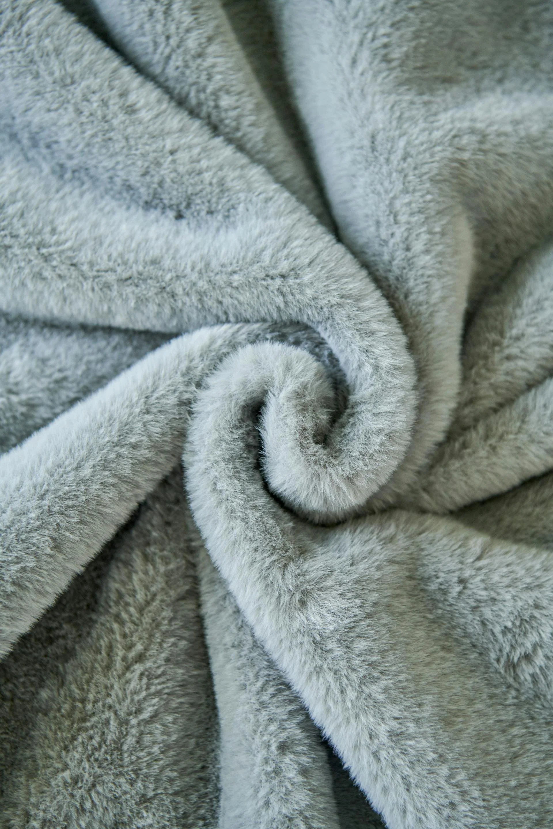 Gros plan de tissu en peluche gris, enroulé en spirale.