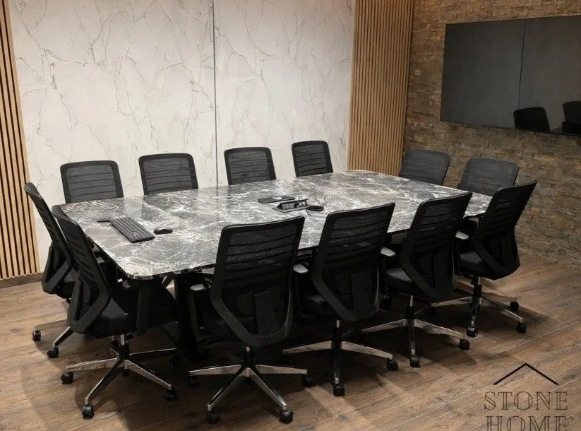 Sala de reuniones con una mesa de mármol y diez sillas negras con ruedas.