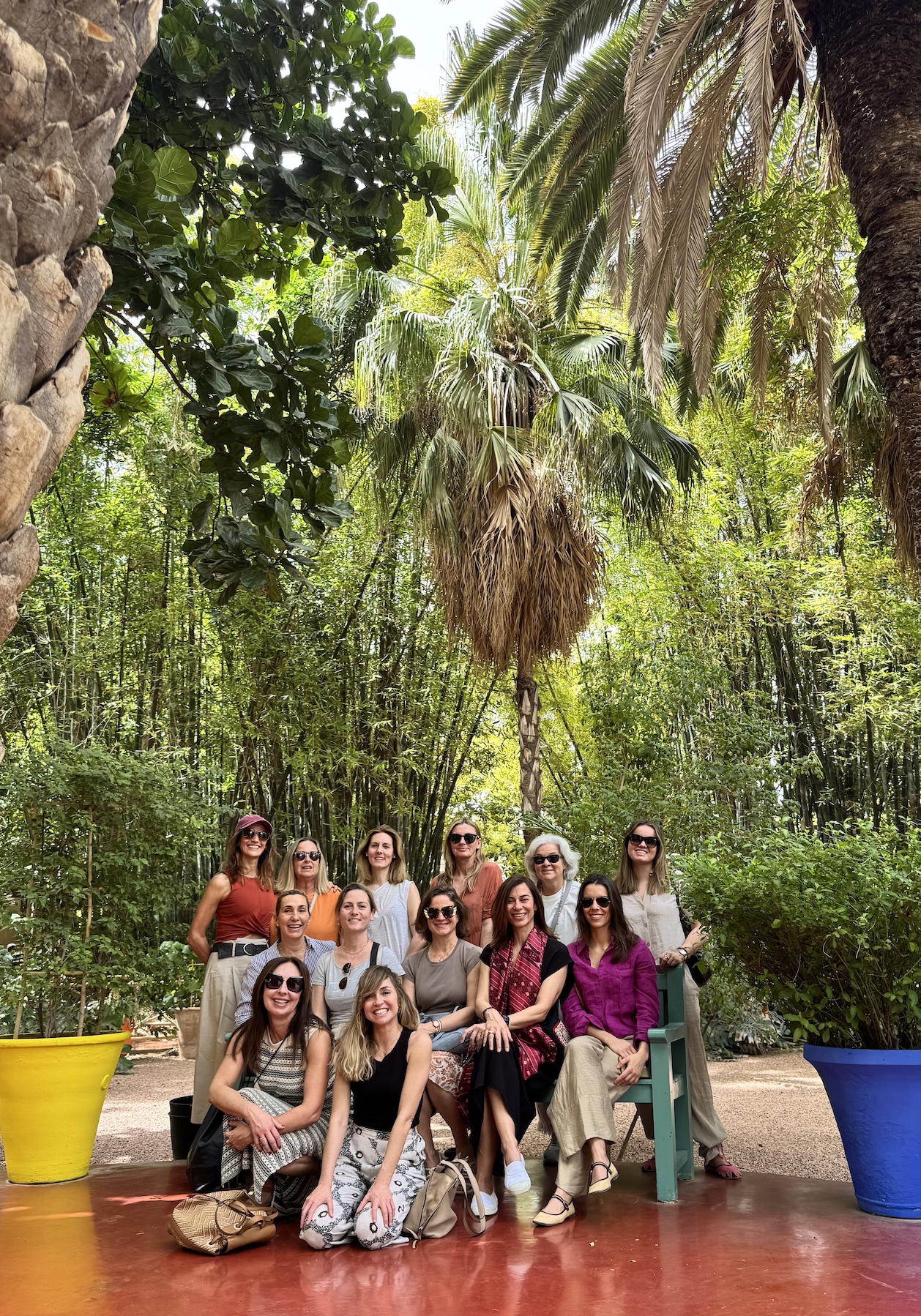 Bancas de descanso con techo de madera y lámparas de mimbre en un espacio al aire libre decorado con plantas y cortinas blancas, en un ambiente de playa o desértico.