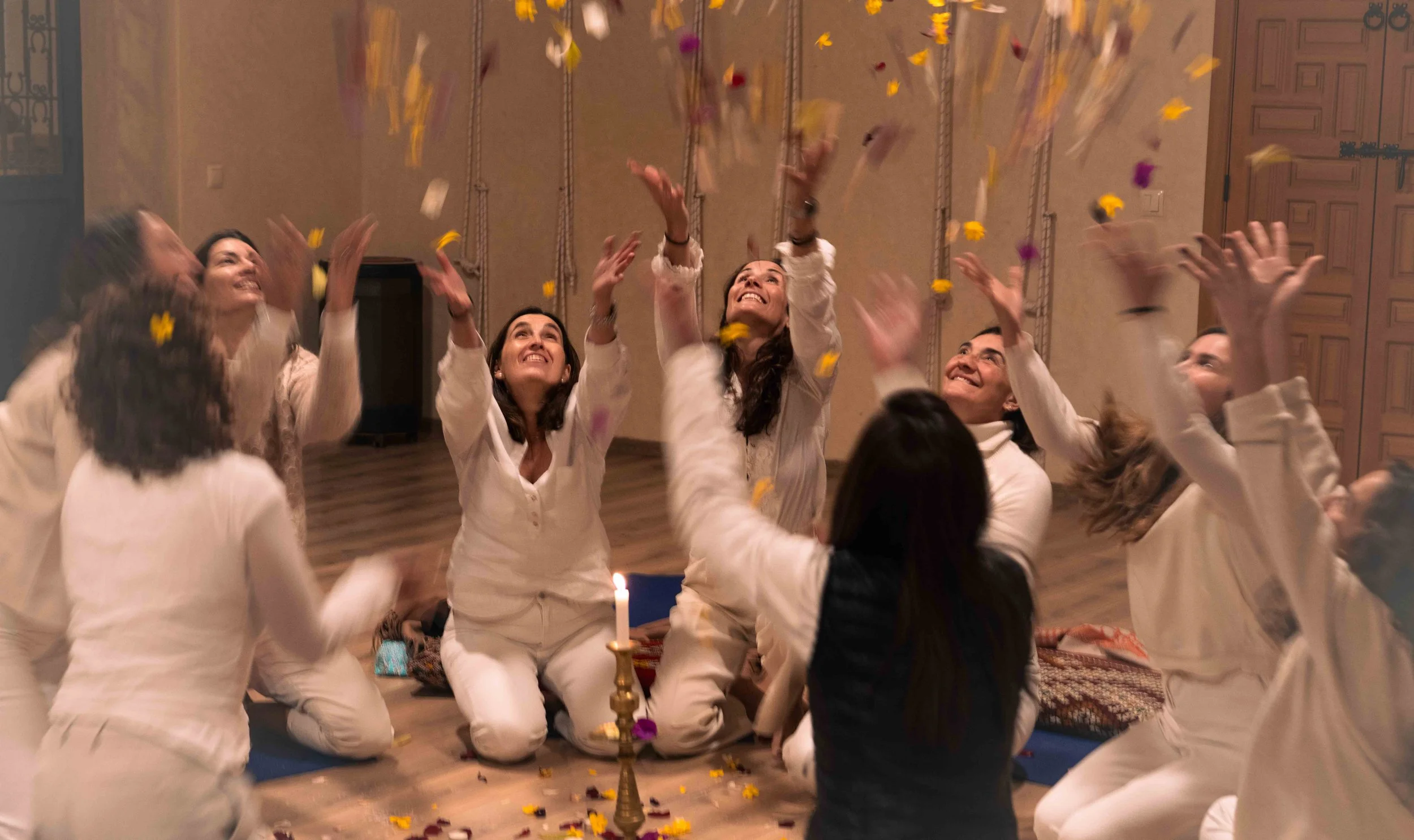 Grupo de personas participando en una ceremonia o celebración, levantando flores y sonriendo en un ambiente decorado con detalles tradicionales.