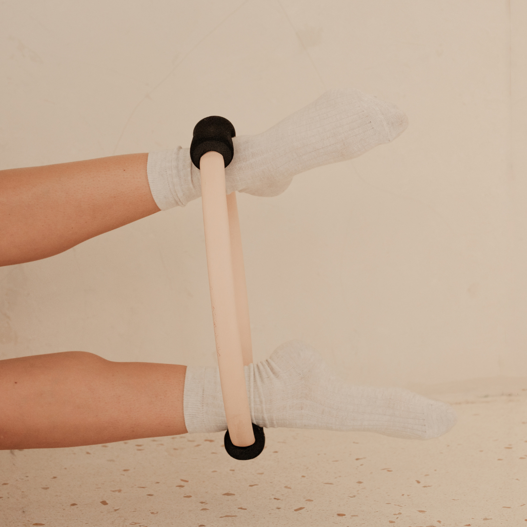 Person using a massage roller on their legs while wearing white socks.