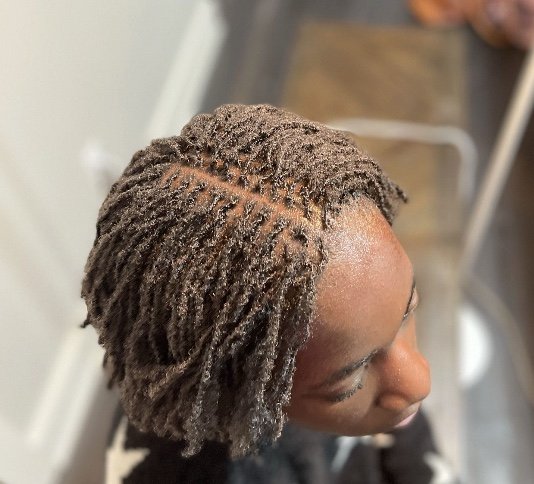 Close-up of a woman with short, textured dreadlocks styled in an off-center part.