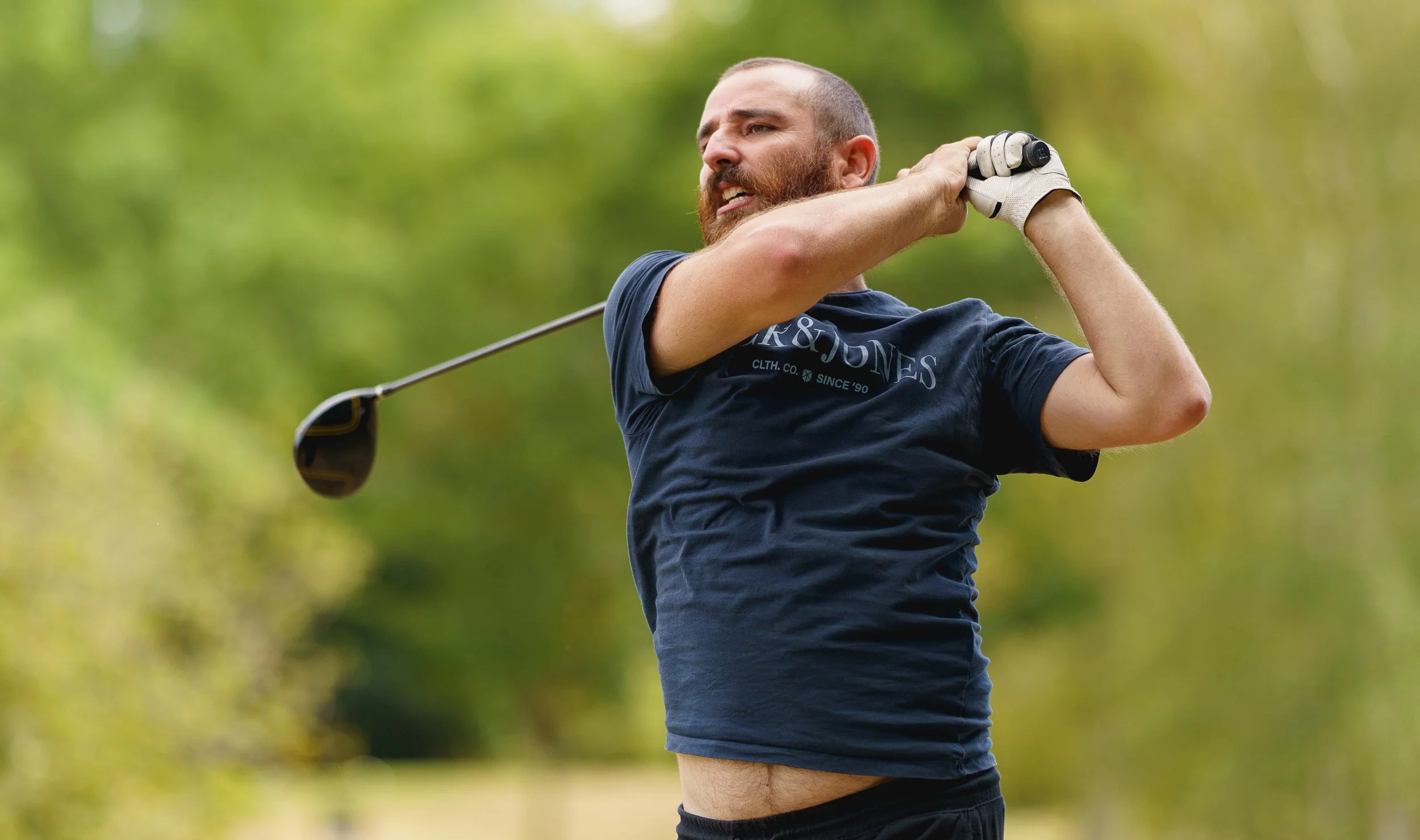 Homme jouant au golf dans un parc, en train de faire un swing avec le club de golf.