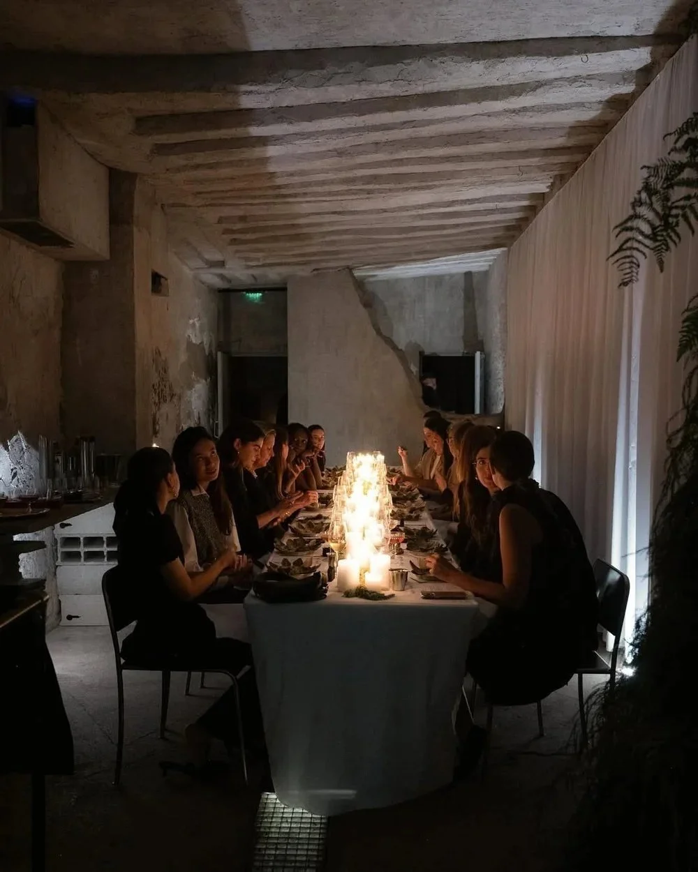 Mesa larga iluminada con velas y mujeres conversando