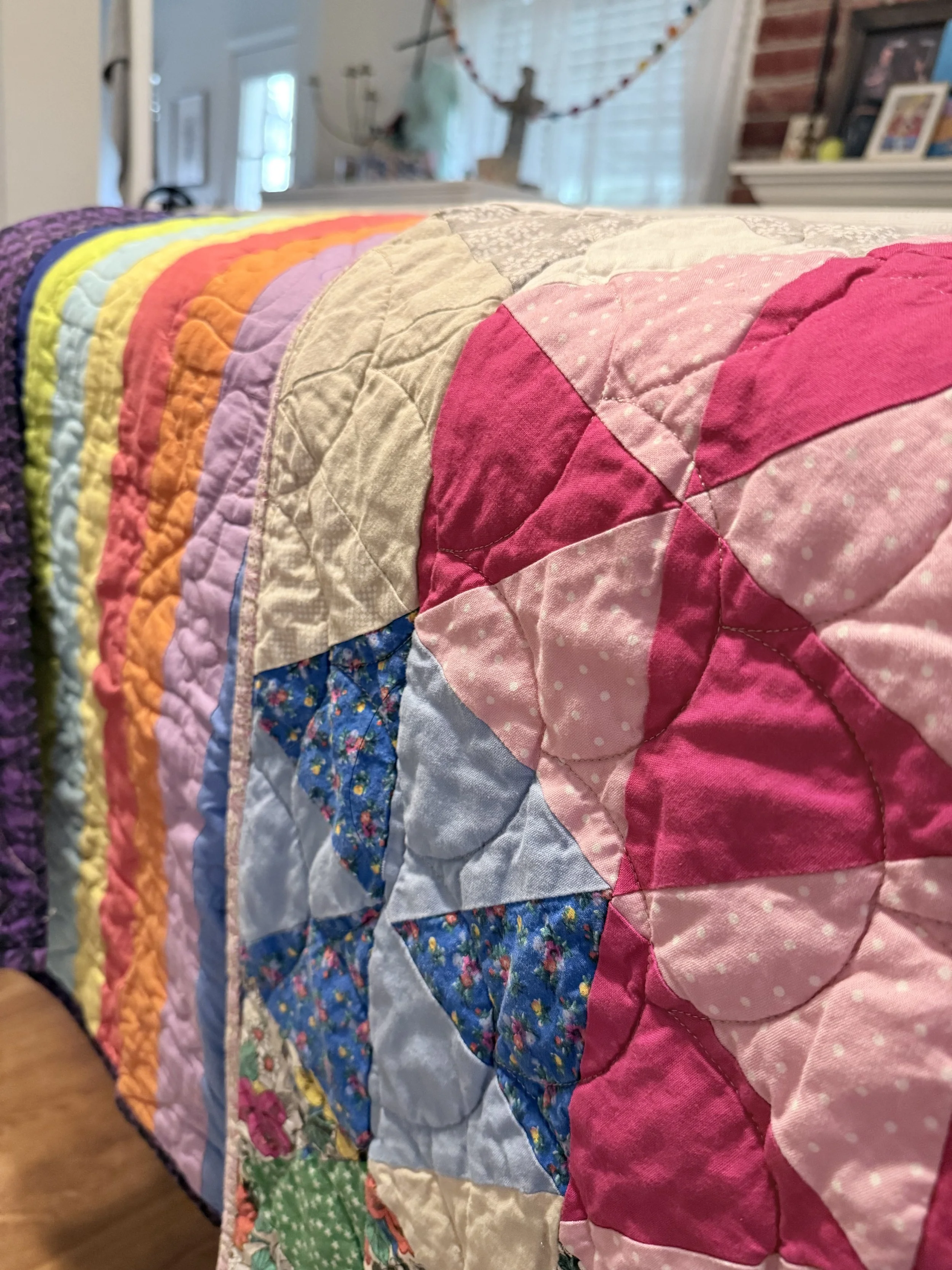Close-up of a colorful patchwork quilt with various patterns and colors, draped on a furniture piece in a cozy room.