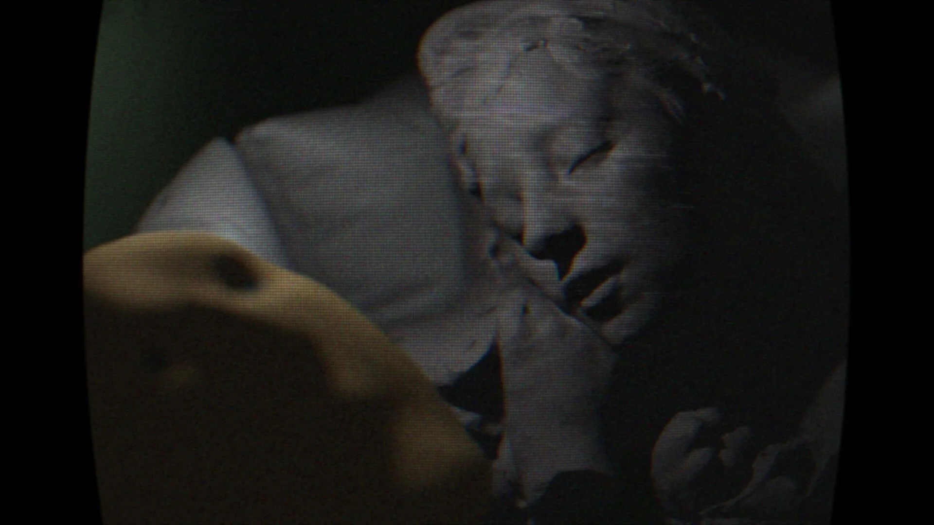 A still from the film "emilycore." A classical statue and a wireframe head lie next to each on a pillow.