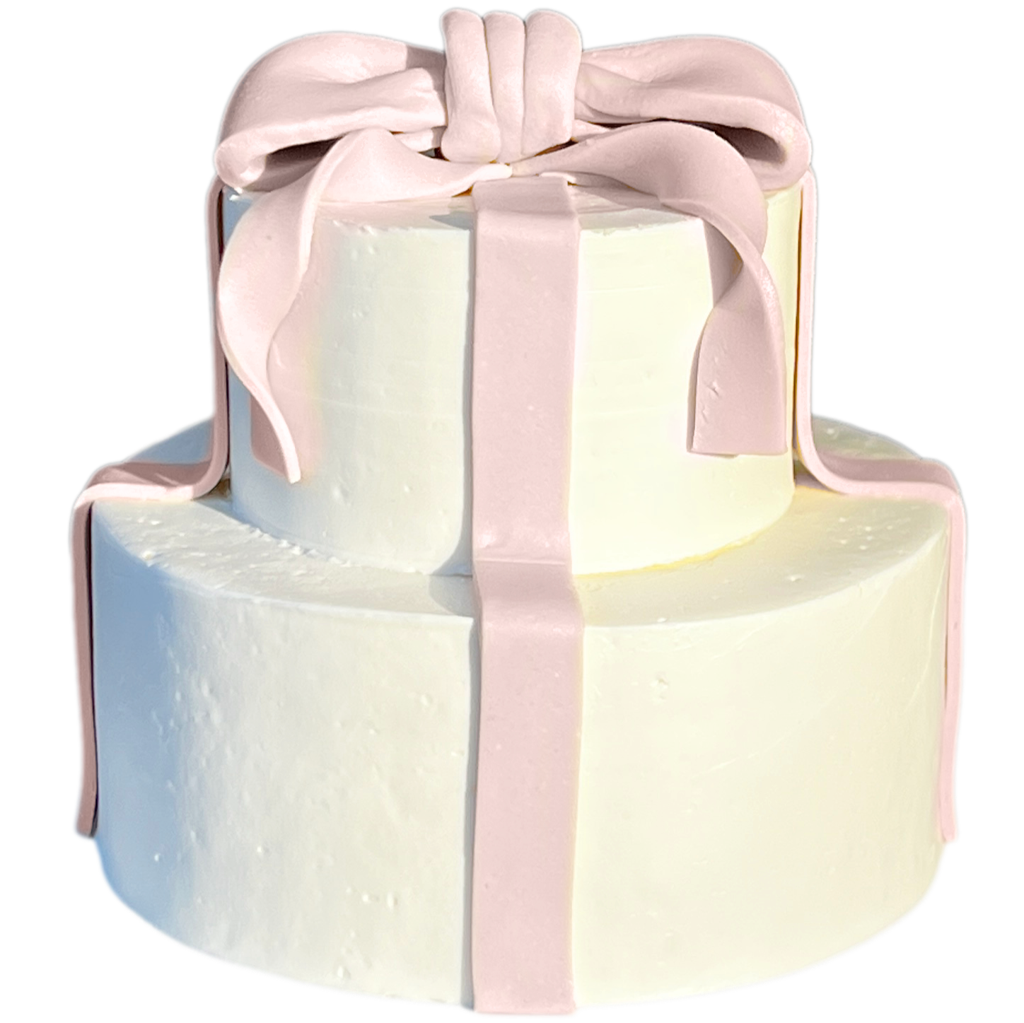 A two-tier white cake decorated with pink fondant ribbon and bow, isolated on black background.