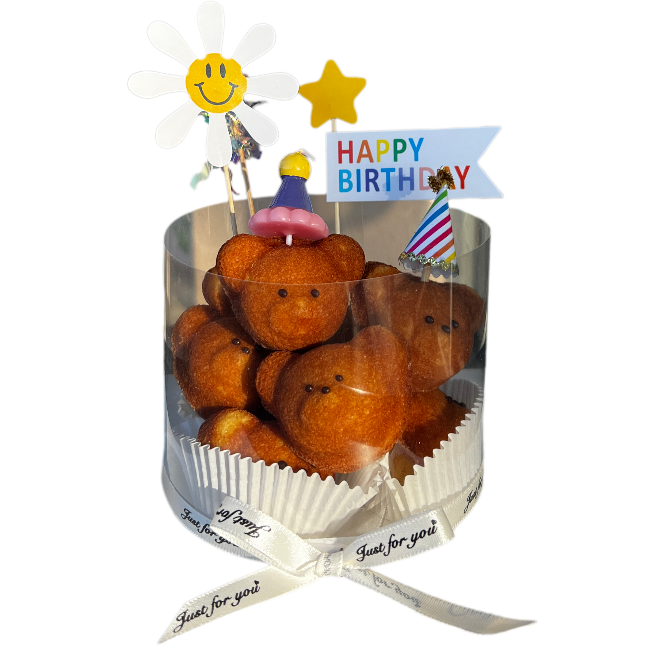 A birthday cake made of bear-shaped fried snacks decorated with small edible faces, topped with colorful party decorations, including a happy sun face, a star, a birthday banner, and a striped party hat, all arranged on a black background.