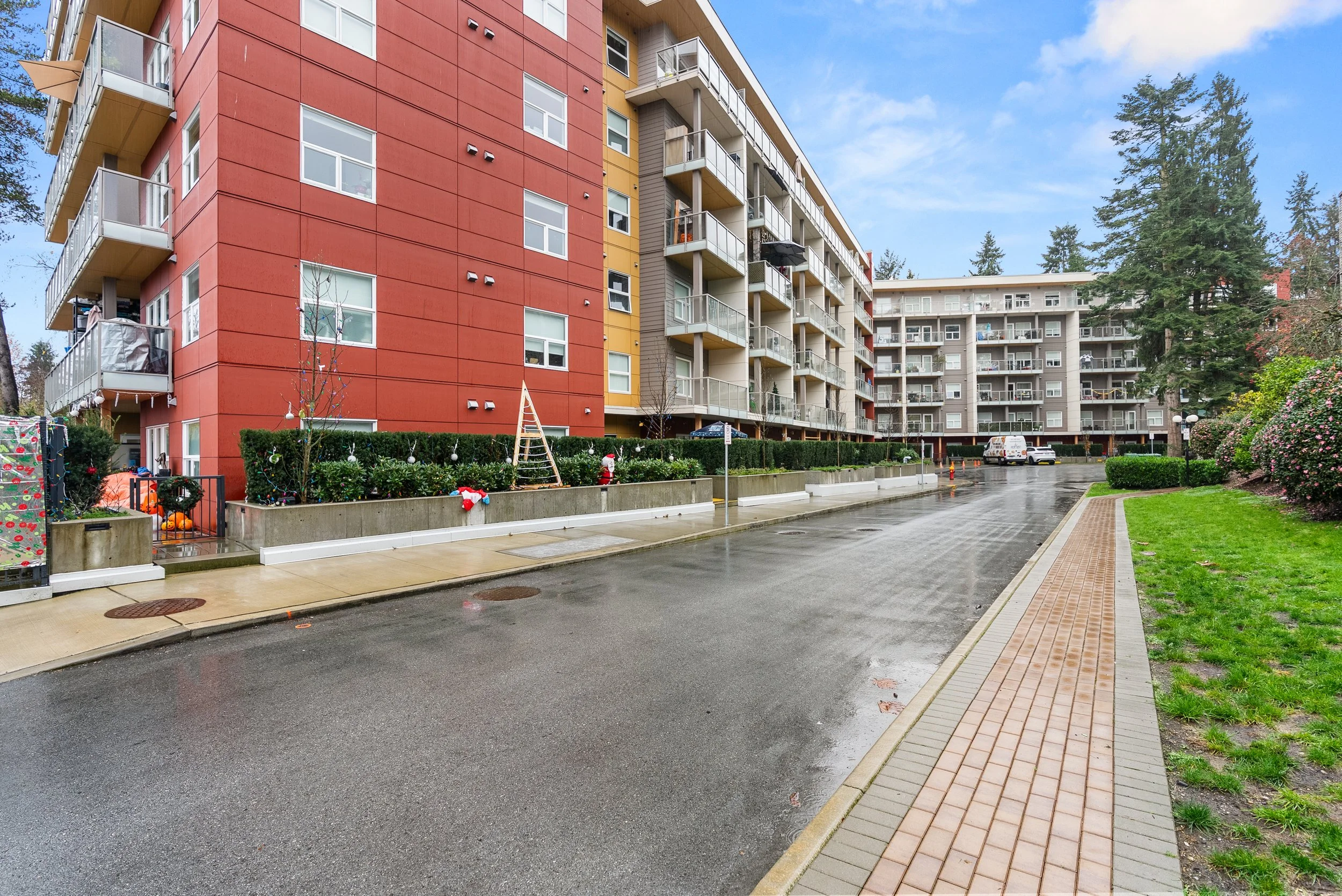 Exterior of a mid-rise cooperative building in Coquitlam with brick facade, balconies, and landscaped front lawn