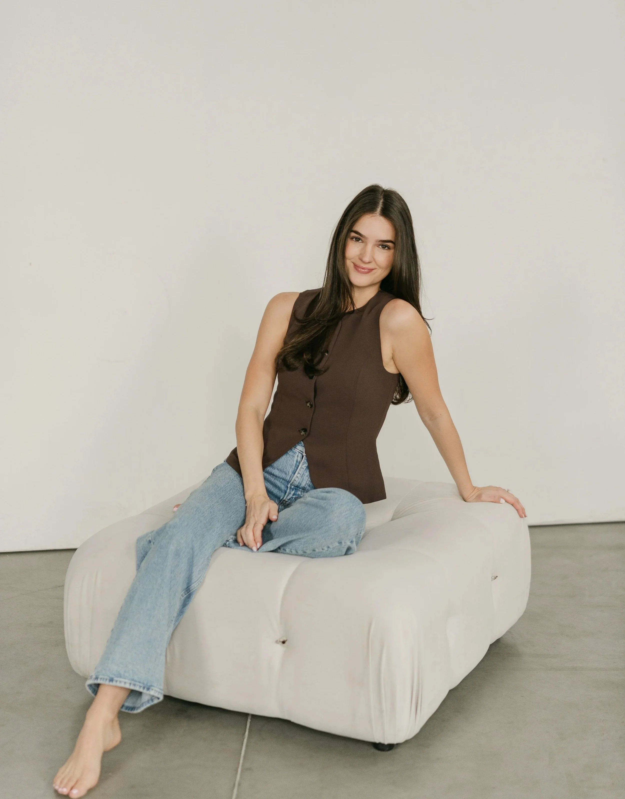 Woman sitting comfortably on a couch in a calm, minimalist space, representing a safe and supportive therapy environment