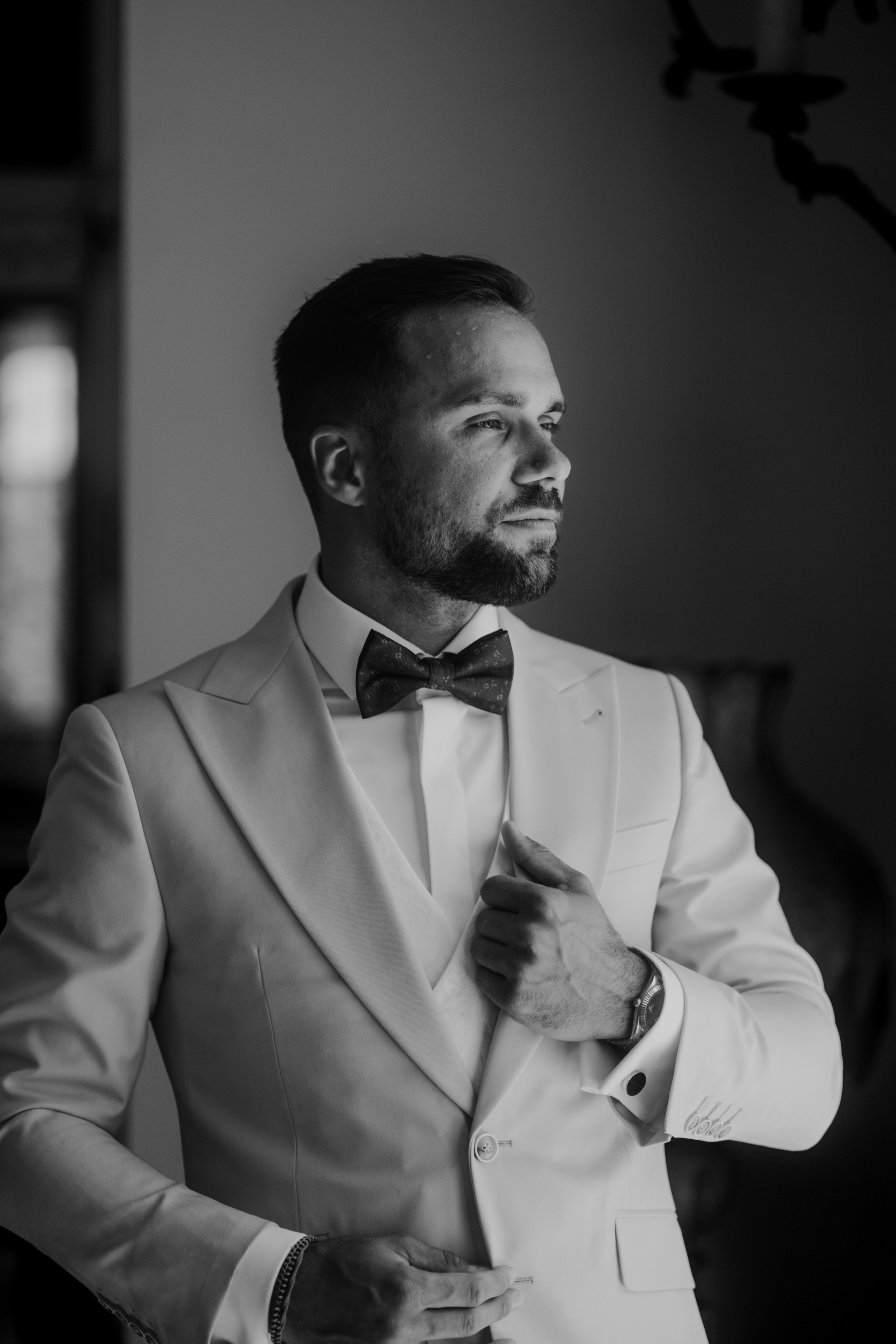 Portrait de marié habillé en smoking blanc avec nœud papillon noir en noir et blanc. Photo de mariage moderne et éditorial. 
