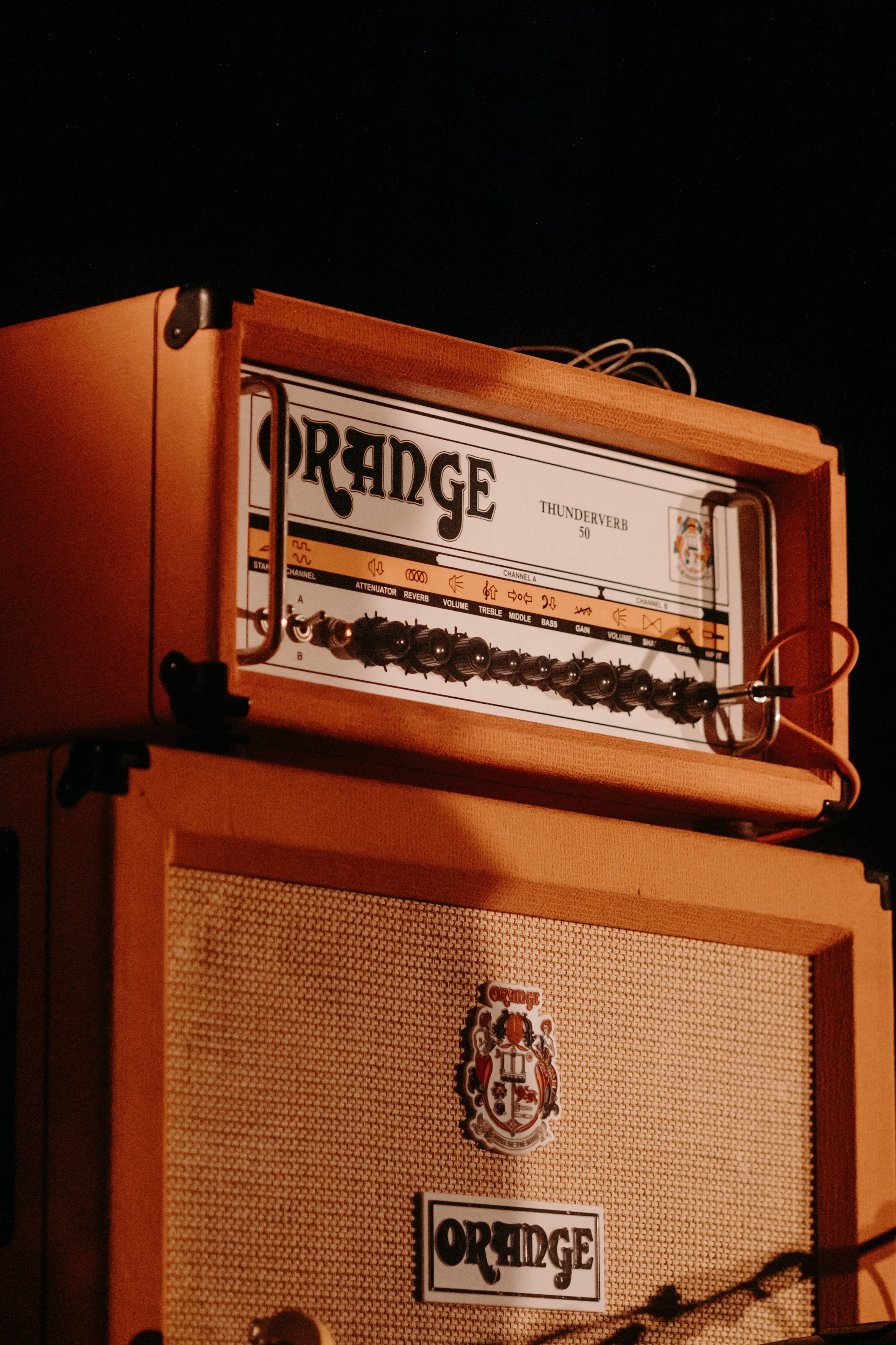 Une caisse amplificateur Orange avec un contrôle de réglage dessus, dans un environnement sombre.