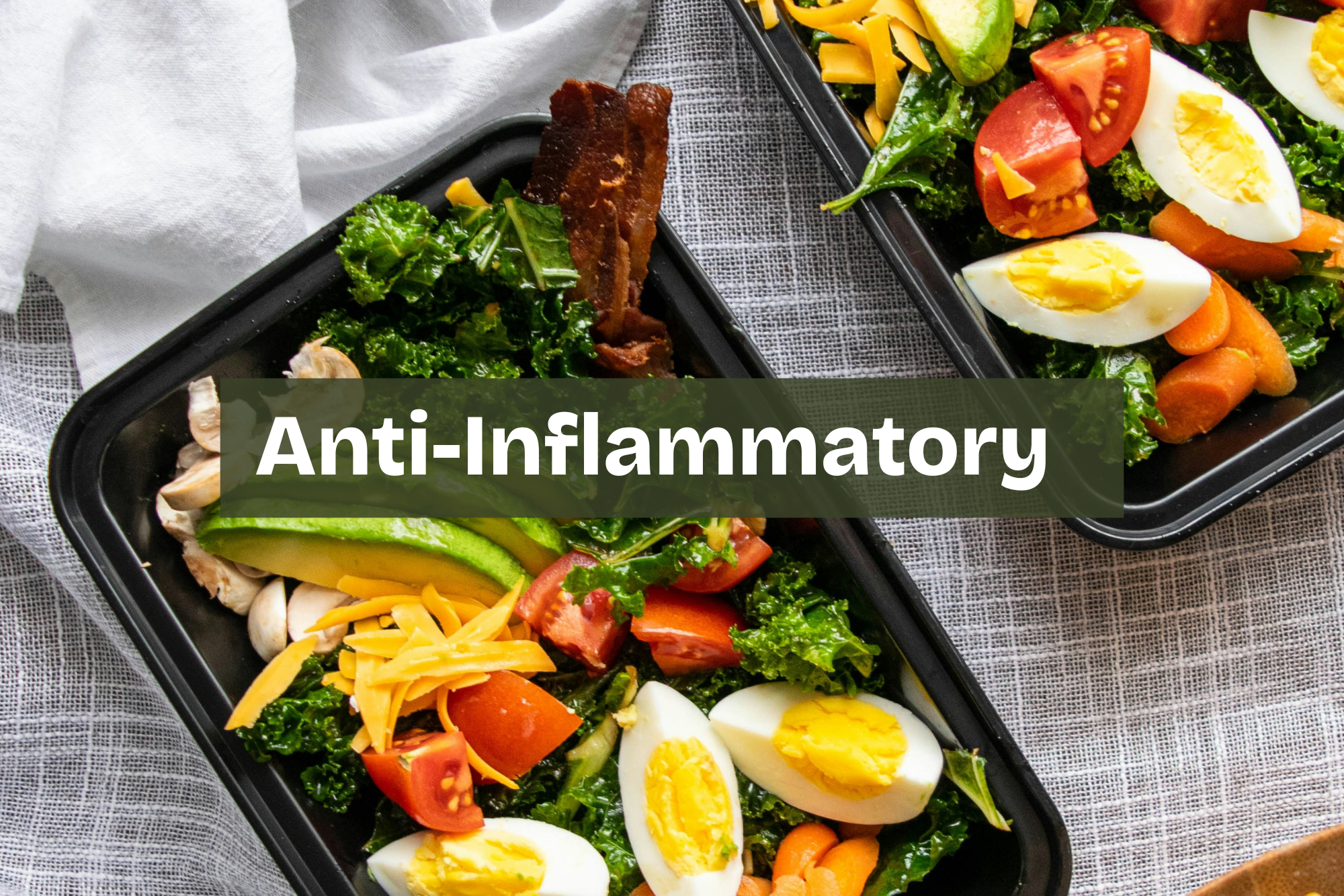 Two black meal prep containers filled with salads, including kale, cherry tomatoes, sliced boiled eggs, shredded cheese, avocado, and chopped vegetables. anti inflammatory whole food meal with vegetables and healthy fats Nourix