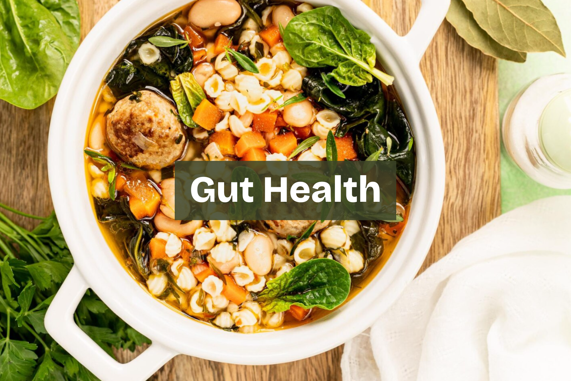 A bowl of soup with vegetables, pasta, and a meatball, garnished with spinach and herbs.  digestive friendly meal with whole foods and balanced nutrients Nourix. gut friendly meal with greens and anti inflammatory ingredients 