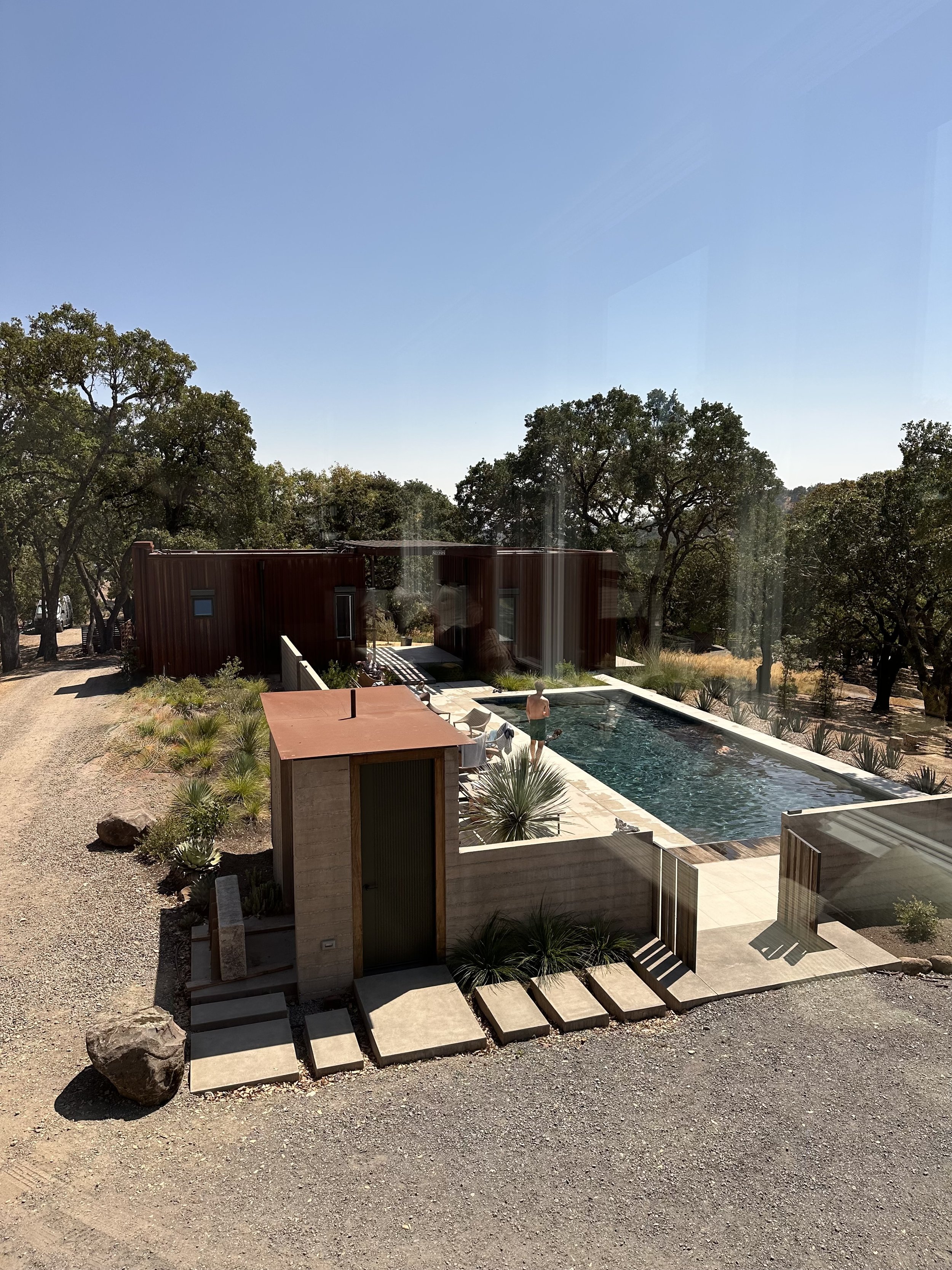 The pool occupies the center of the original home lost in fire, and the new structures gather round it