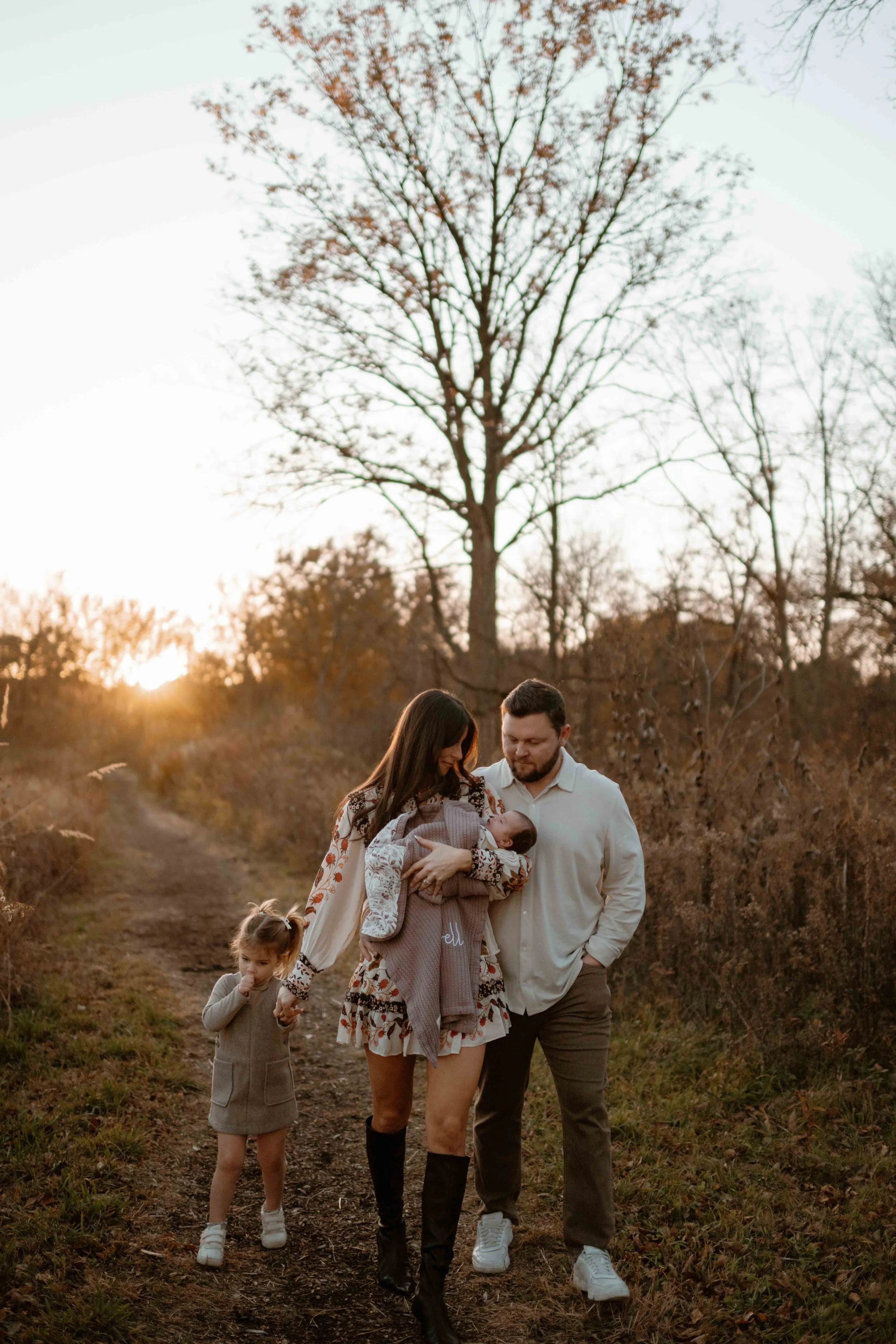 family of four admiring new baby at sunset at the Morton Arboretum Lisle IL 