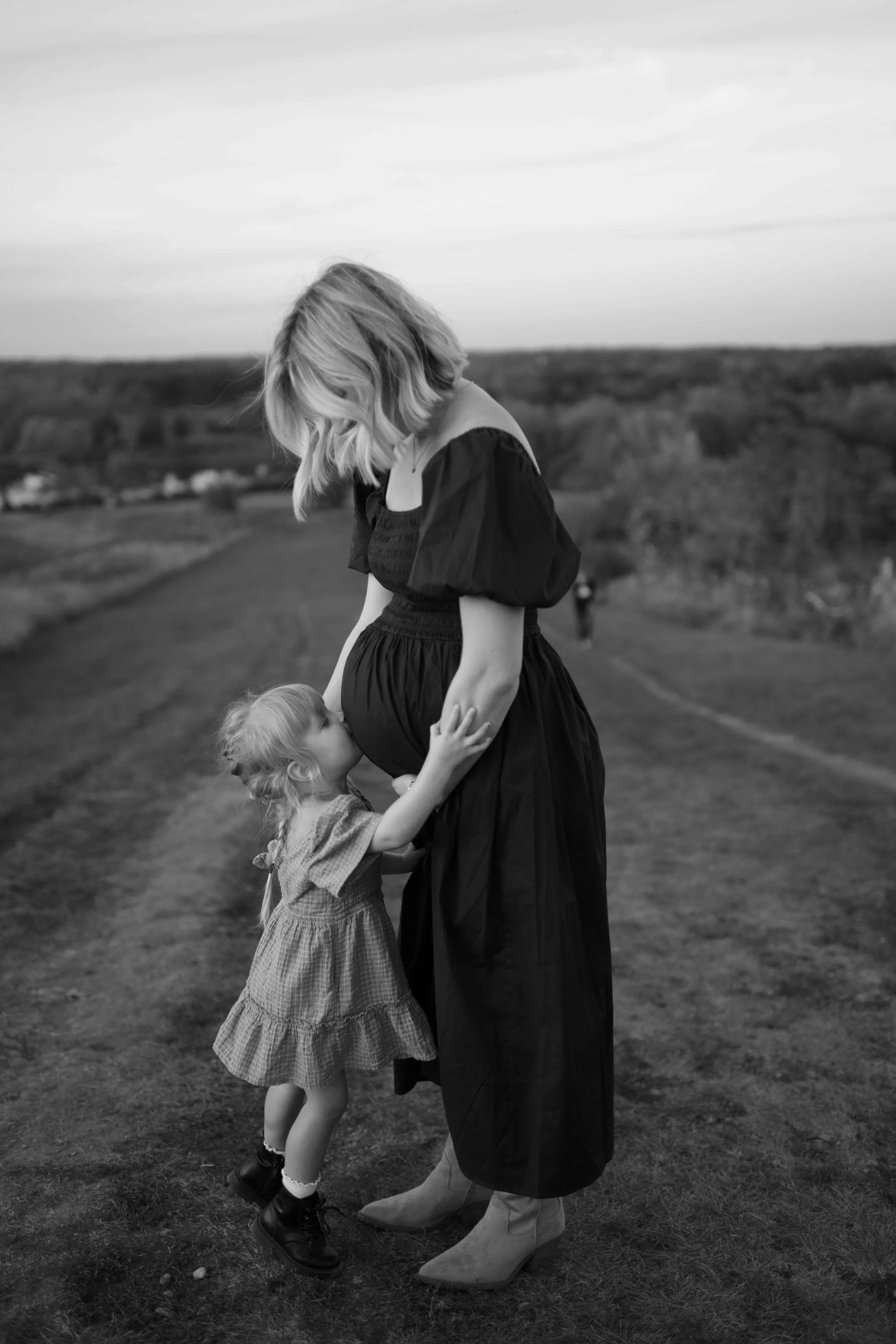 black and white photo of 3 year old kissing mom's pregnant belly at blackwell forest preserve in wheaton IL