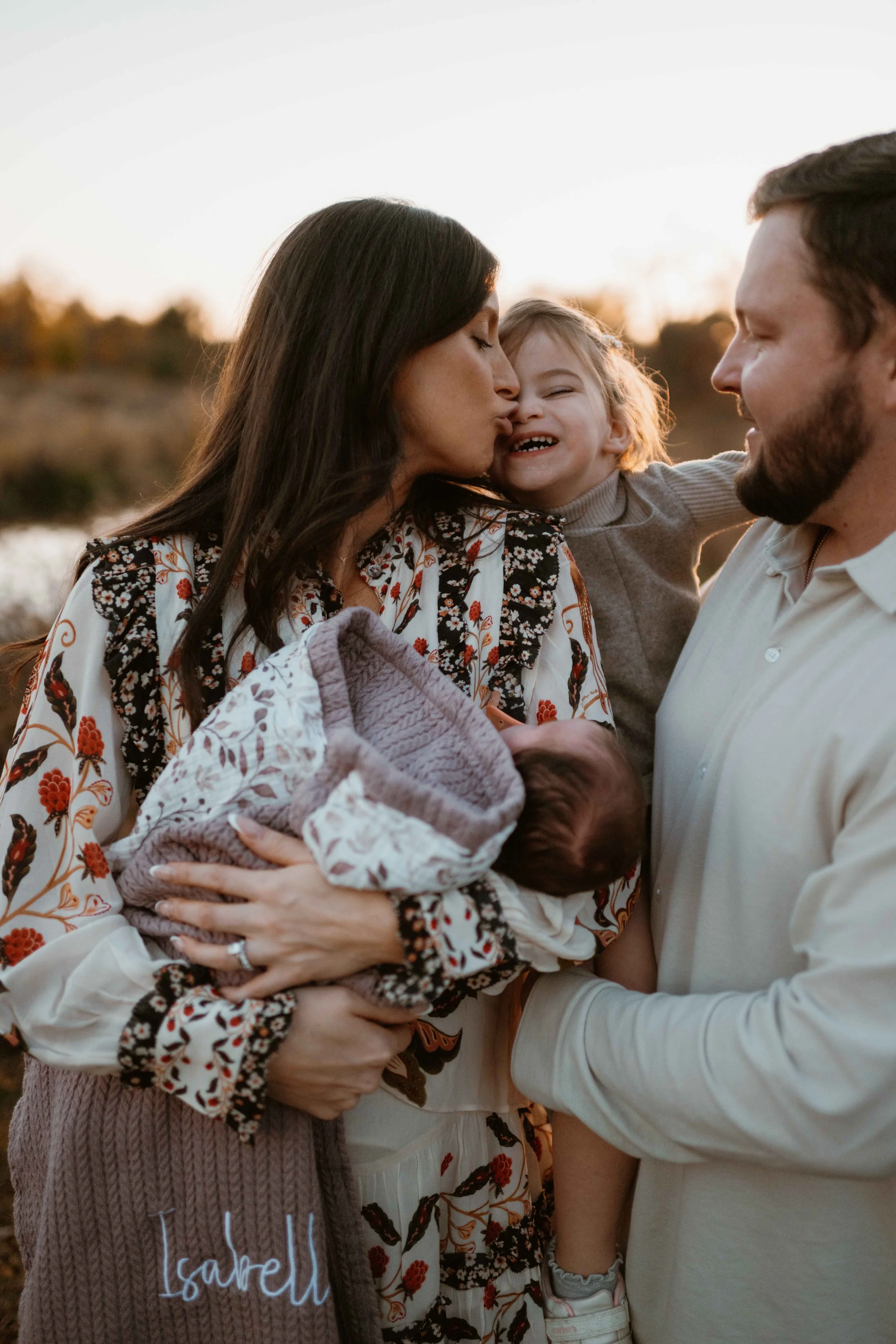 mom kissing daughter and holding new baby at sunset at the Morton Arboretum Lisle IL 