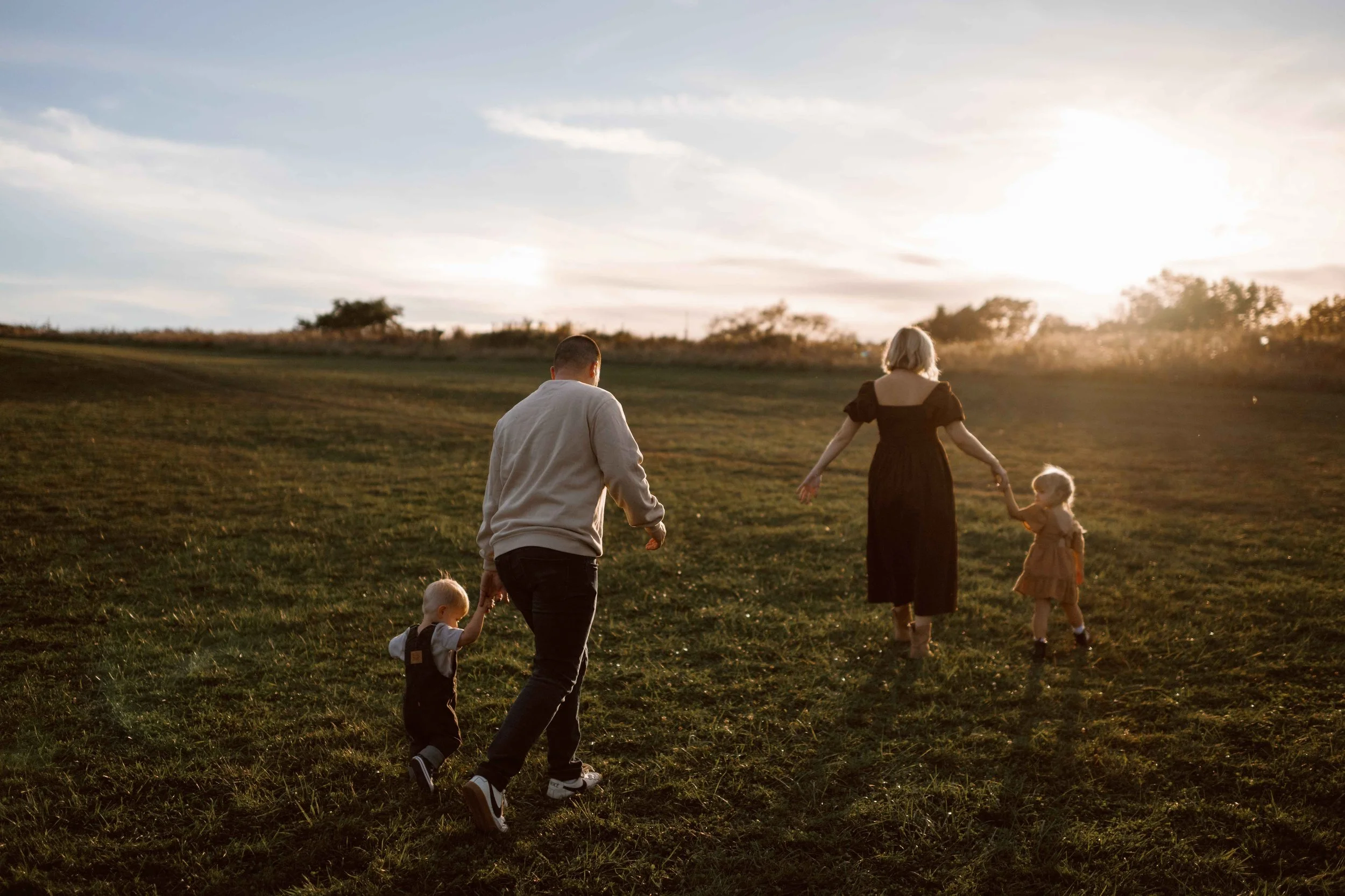 mom and dad holding their kids' hands at sunset at Blackwell Forest Preserve Wheaton 