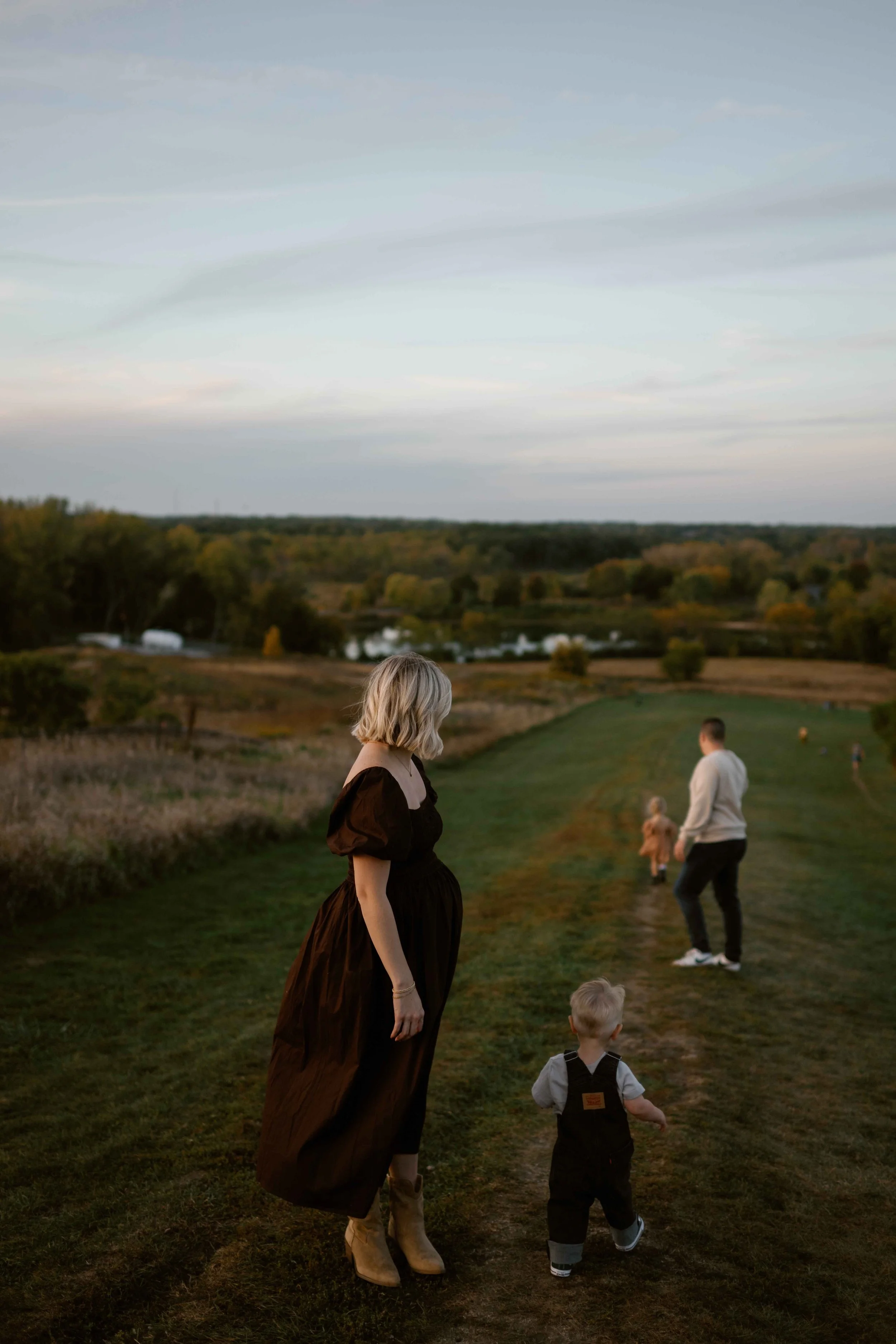 Pregnant Mom and dad chasing their two toddlers down a hill at Blackwell Forest Preserve