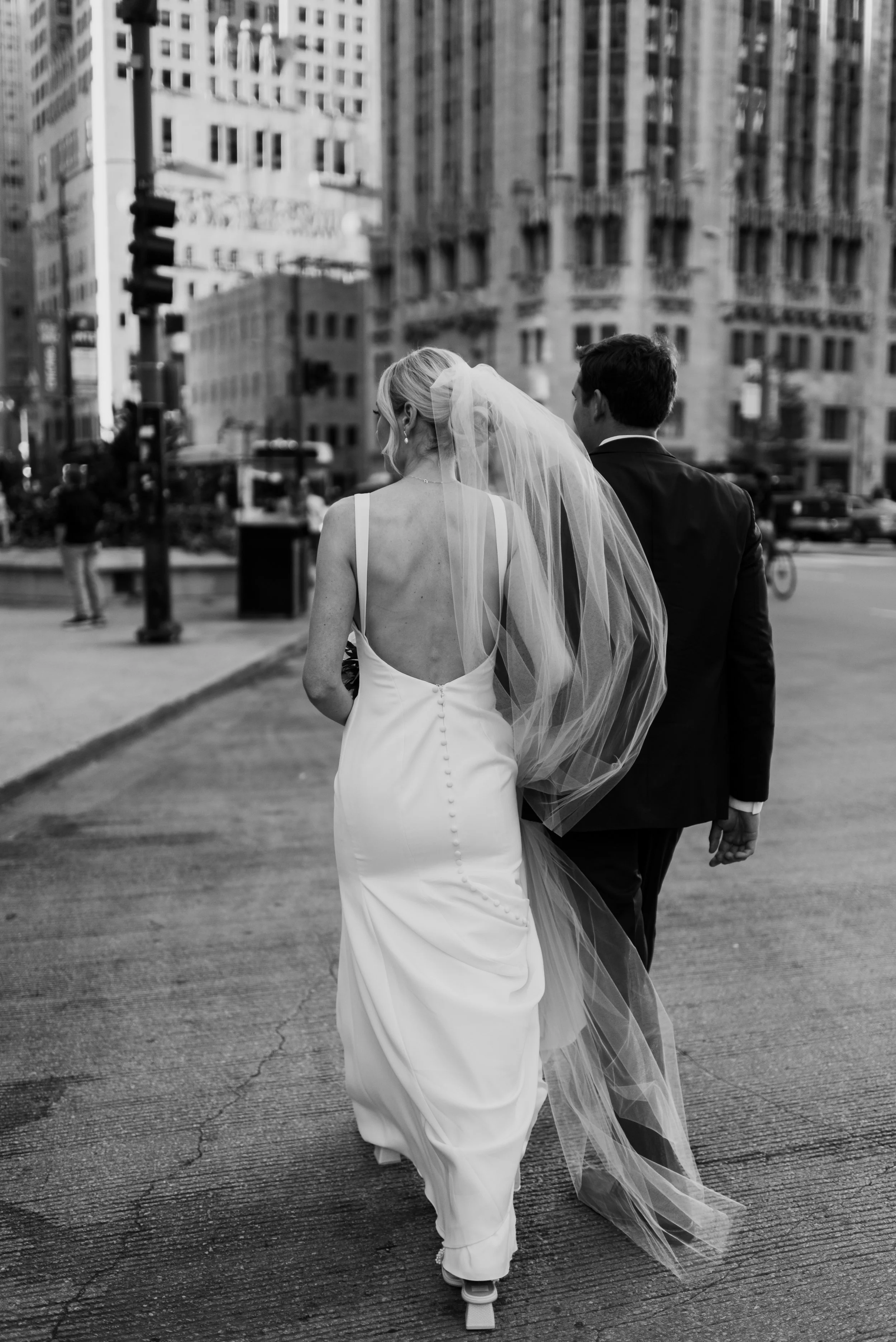 Black and white photo of a bride and groom walking arm in arm in the streets of Chicago Illinois