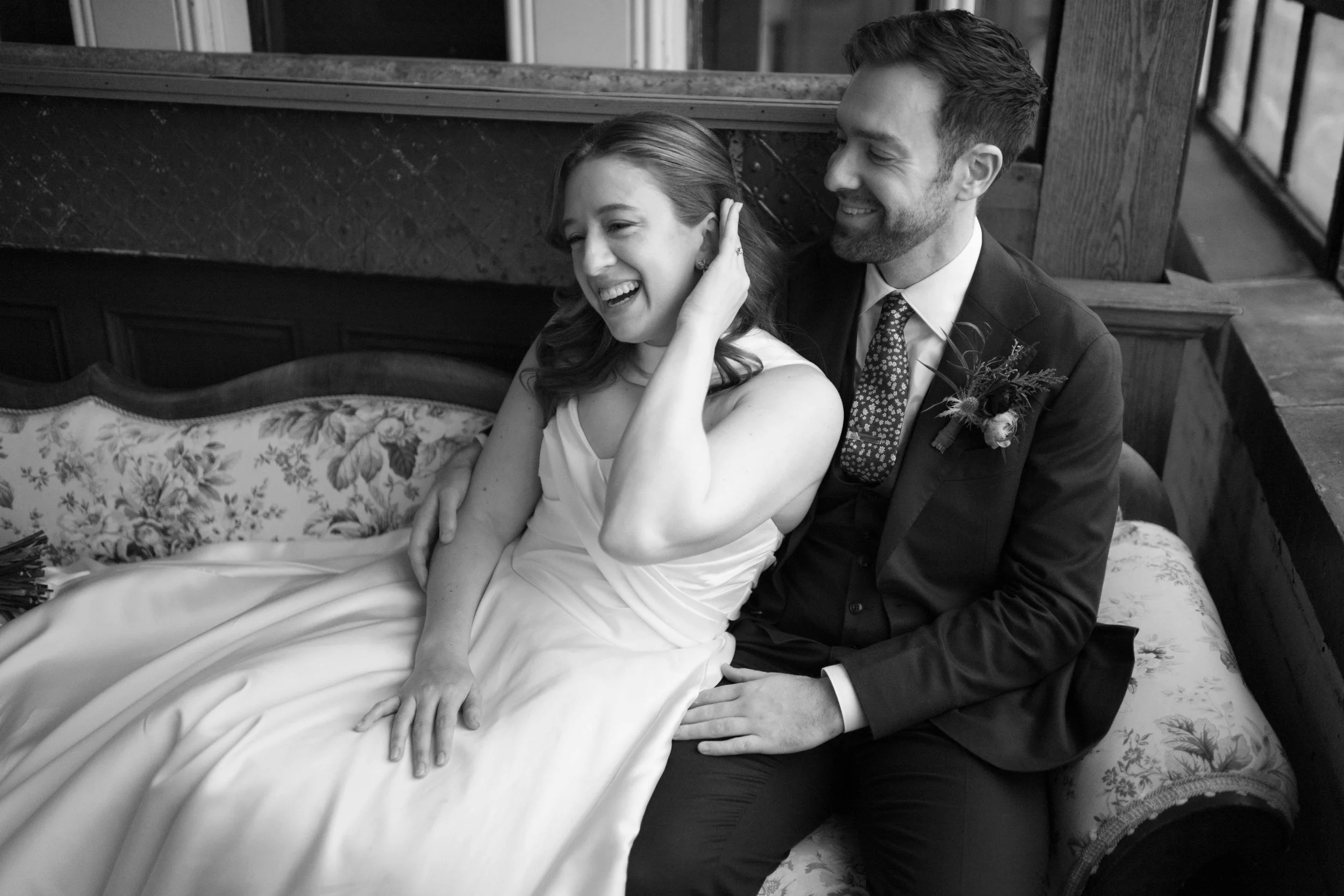 Black and white photo bride and groom laughing on couch at Salvage One in Chicago
