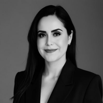 Retrato en blanco y negro de una mujer con cabello oscuro, vestida con un saco negro y sonrisa sutil