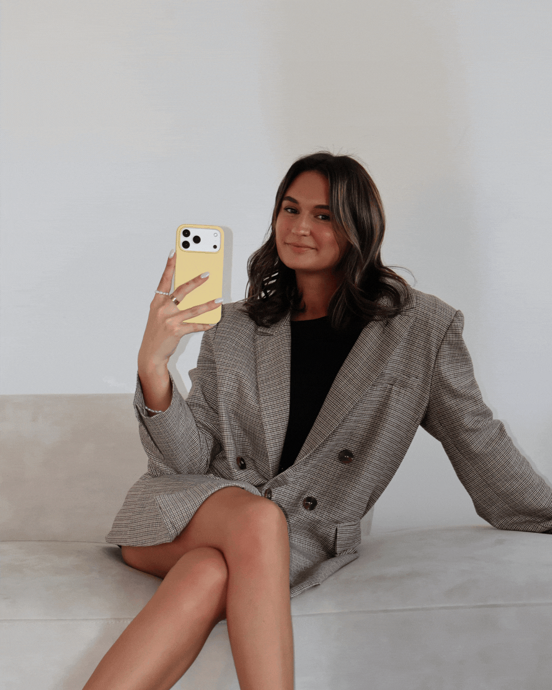 A gif of photos of girl with shoulder length brown hair in a large blazed in a bright light setting, posing with her iPhone.
