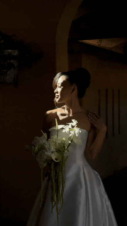 Low lit image of a bride looking out of a window.