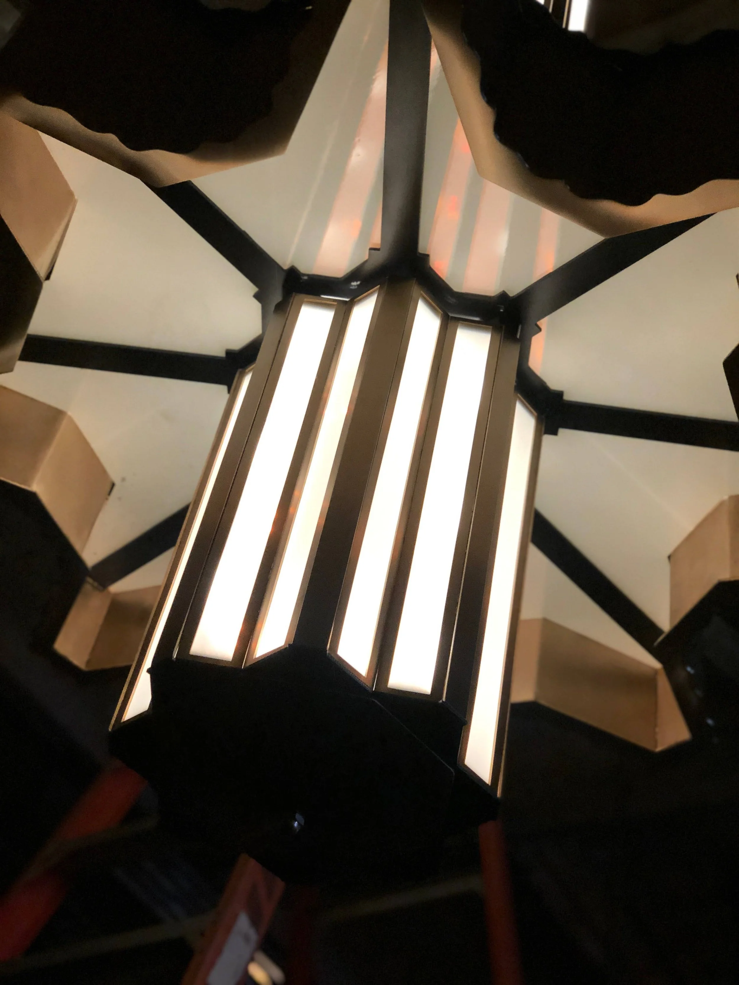Close-up photo of a modern ceiling light fixture with multiple illuminated vertical panels, viewed from below.
