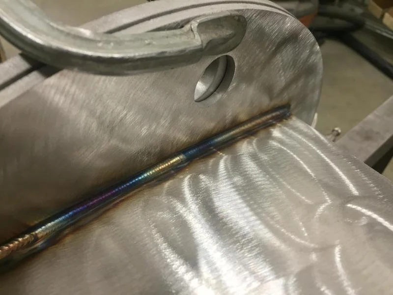 Close-up of a stainless steel welding process on two metal surfaces.