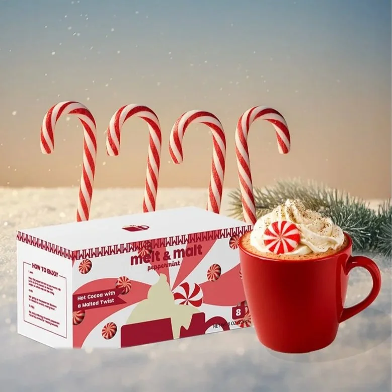 A peppermint hot chocolate drink topped with whipped cream and a peppermint candy, with a box of peppermint hot cocoa and candy canes in the background, set against a wintery, snowy backdrop.