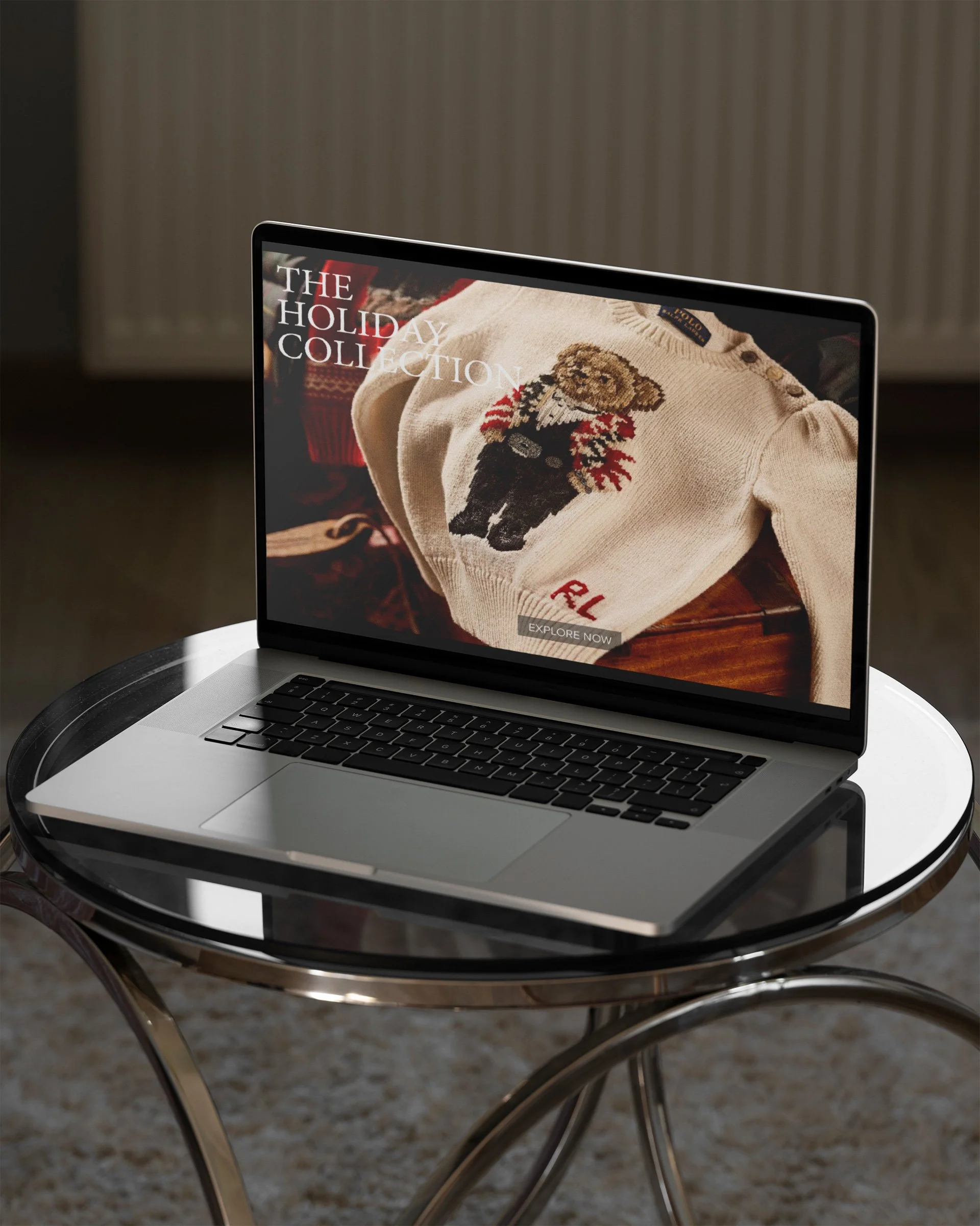 A silver laptop on a glass table displaying a clothing website featuring a holiday-themed sweater with a bear design. In the background, a room with a radiator and beige wall.