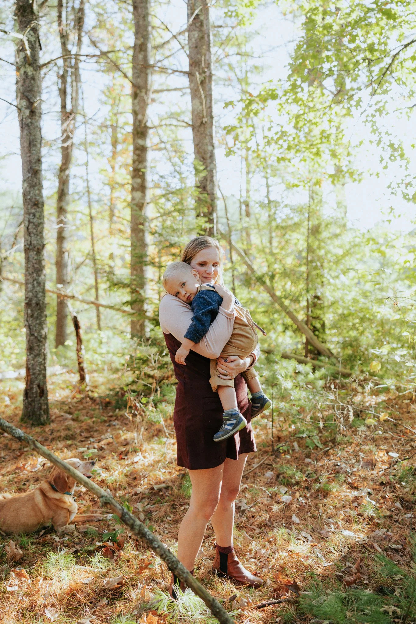 Woman carrying a young boy in a forest.