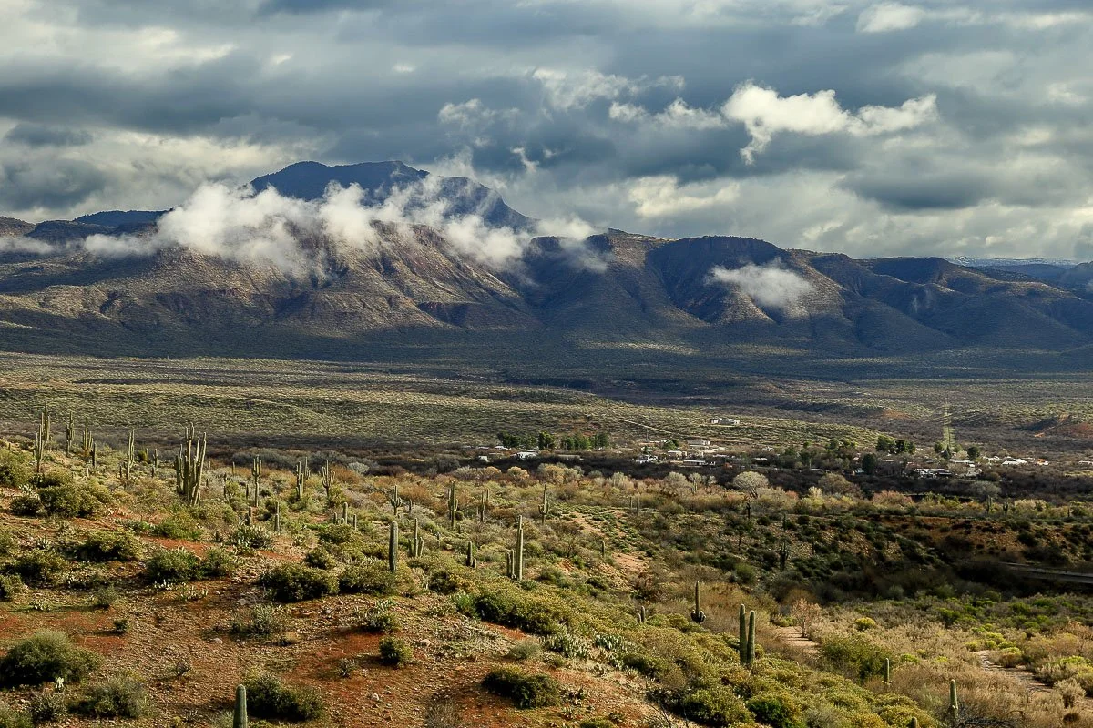 Storm clouds intermingle with mountains above the desert in Tonto Basin.