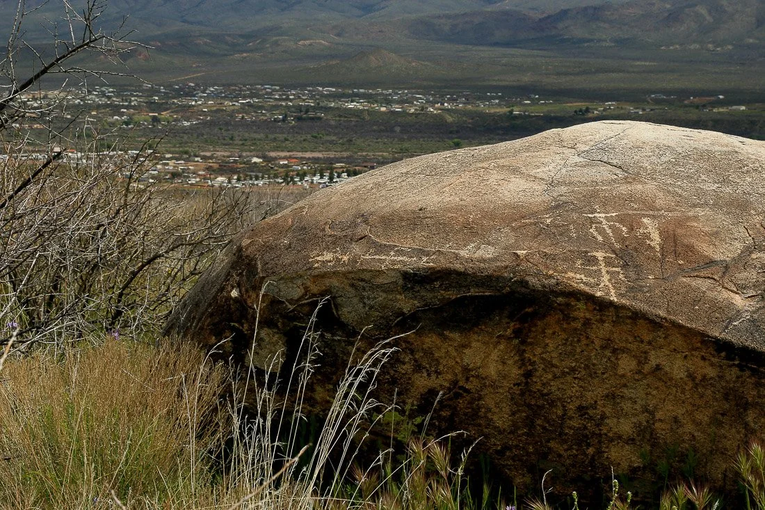 Petroglyphs on a large boulder with the village of Tonto Creek in the distance. 