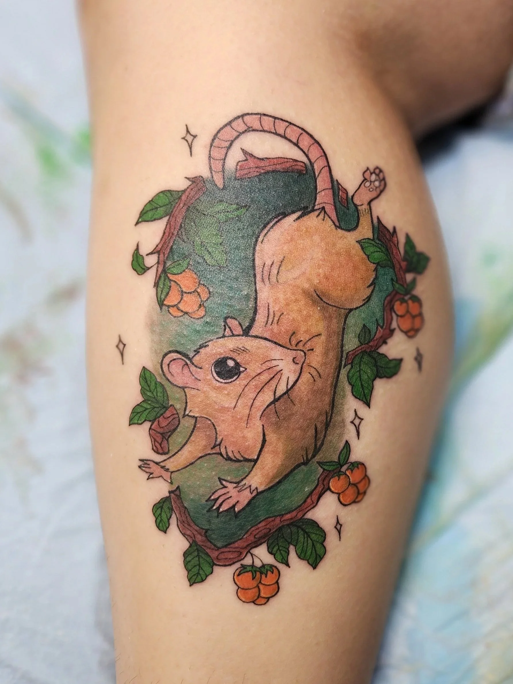 Tattoo of a cute, cartoon-style ferret surrounded by green leaves, brown branches, and orange berries.