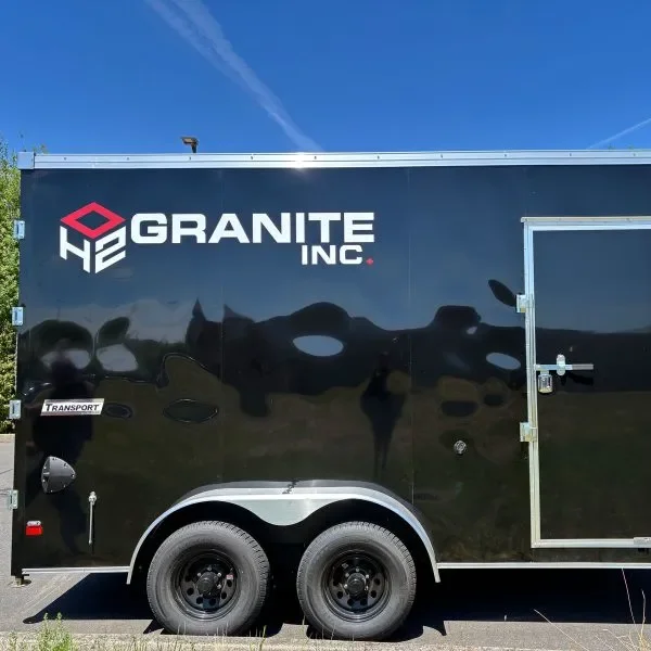 Black enclosed trailer with 'Granite Inc.' logo in white and red, side door, and two wheels.