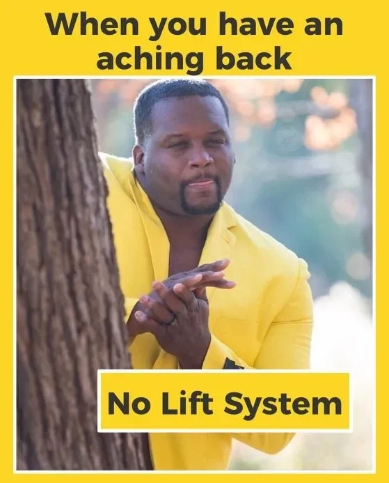 A man with a contemplative expression, wearing a yellow suit, standing behind a tree outdoors with blurred background of trees and sunlight. Caption reads, 'When you have an aching back, No Lift System'.