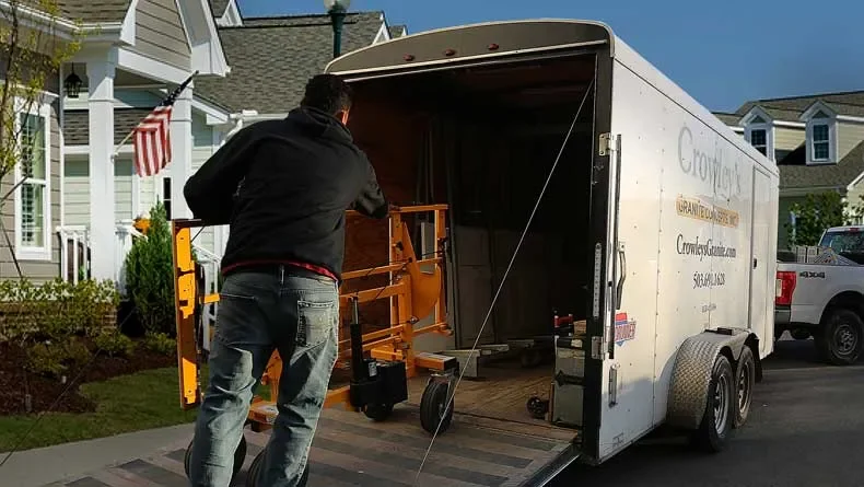 Person loading an orange indoor camping bed into a white enclosed moving truck parked in a suburban neighborhood.
