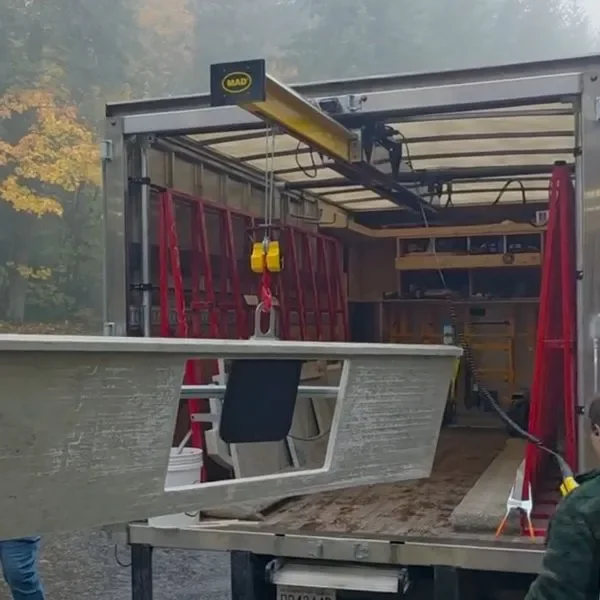 Inside a truck, a construction or utility workspace with a red ladder, yellow hoist, and various tools and equipment. The truck bed is empty, ready for use.