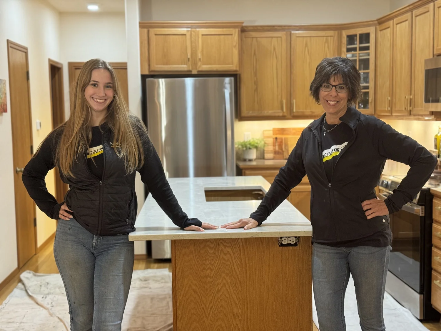Two novice installers standing beside the quartz island they installed using the No Lift System Power Tilt installation cart