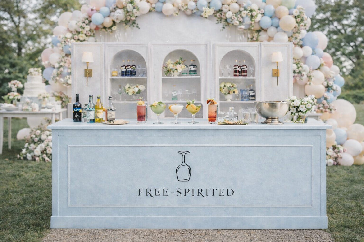 A light blue bar with the words 'FREE-SPIRITED' and a minimalist wine glass icon, set against a backdrop of flowers and balloons in pastel colors, with various colorful cocktails on the bar.