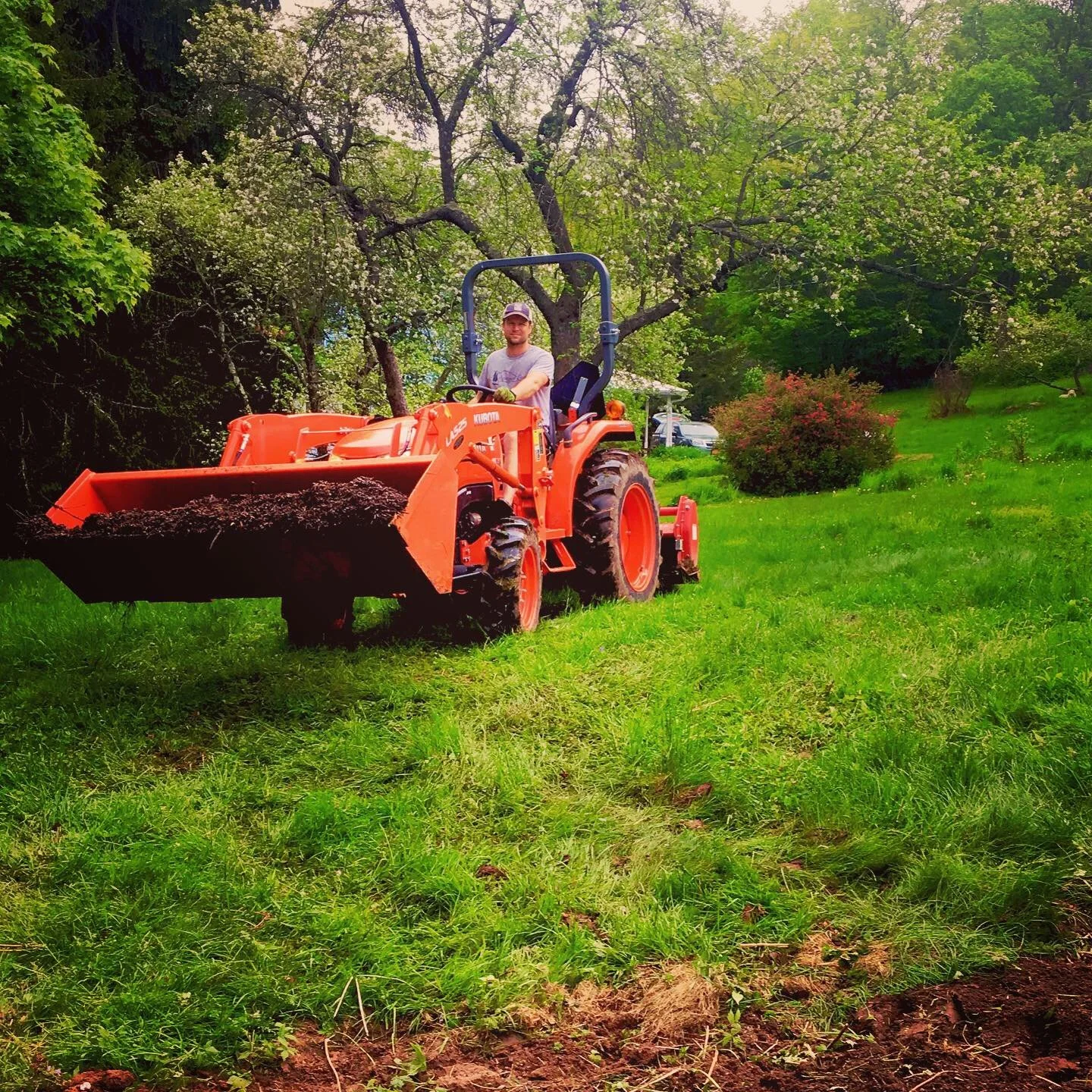 A person on a tractor delivering healthy organic soil to restore and revitalize a garden with poor native soil