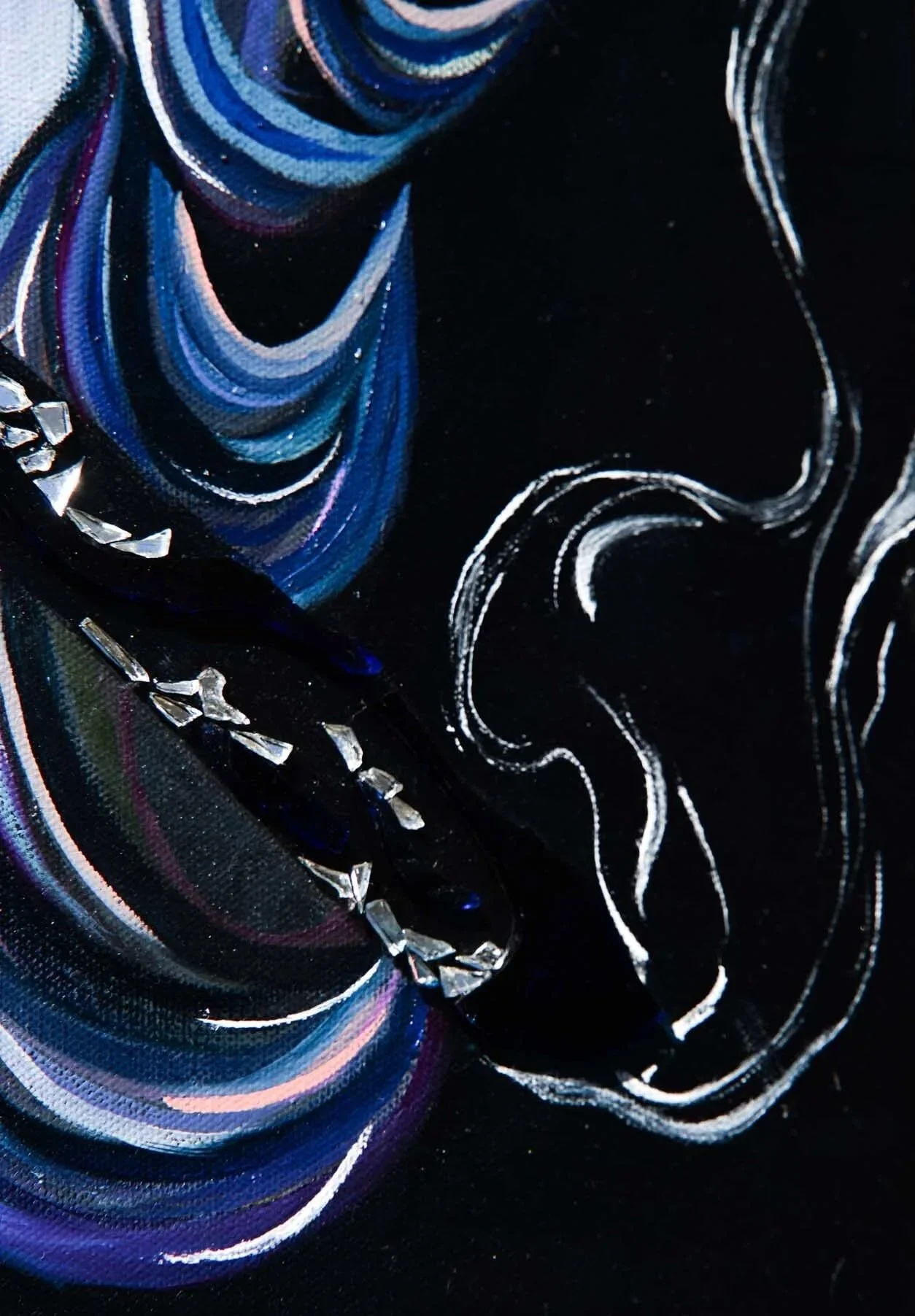 Close-up photograph of a dark fabric with blue, pink, and white swirling patterns, embellished with silver rhinestones.